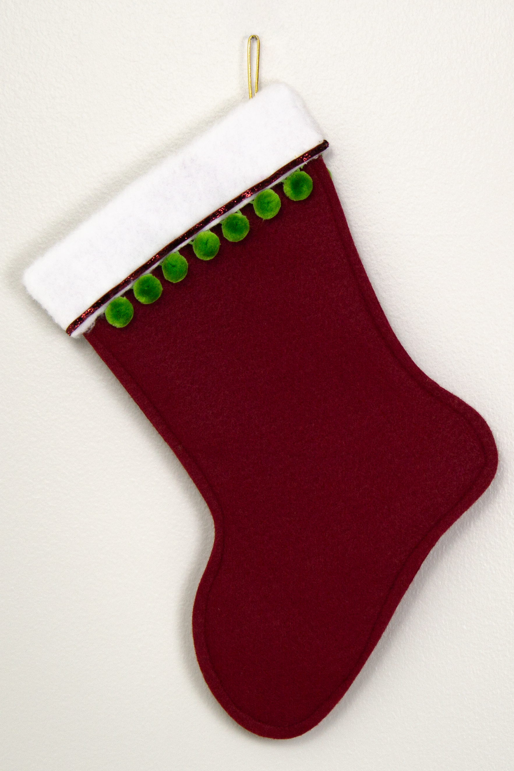Christmas stocking in ruby red felt with gold stars, green pom poms and decorations in red, green and gold. (Back of Akita stocking)