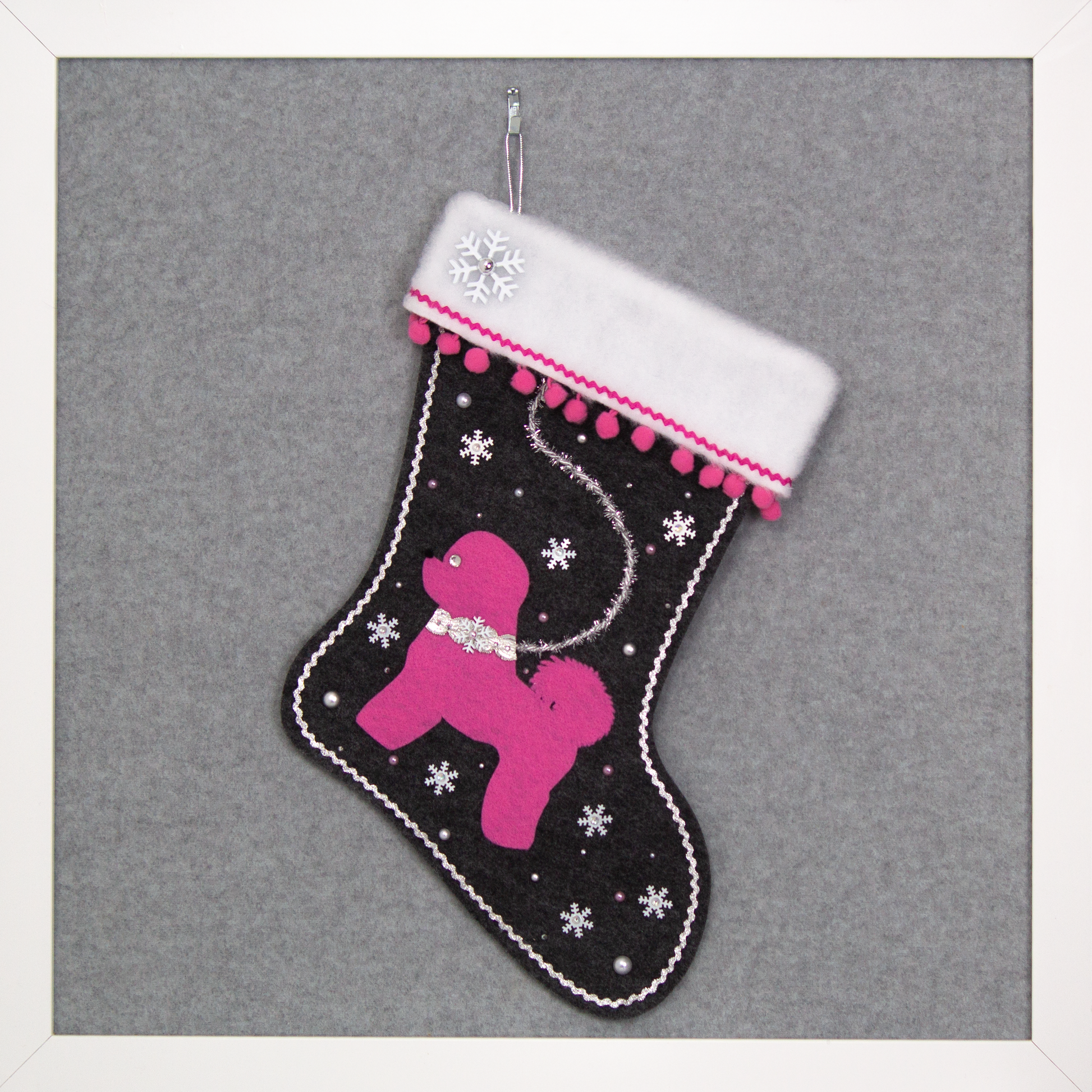 Bichon Frise dog in candy pink felt Christmas stocking on charcoal gray felt with pom poms, tinsel, snowflake sequins and decorations in pink and silver. (Front of stocking)
