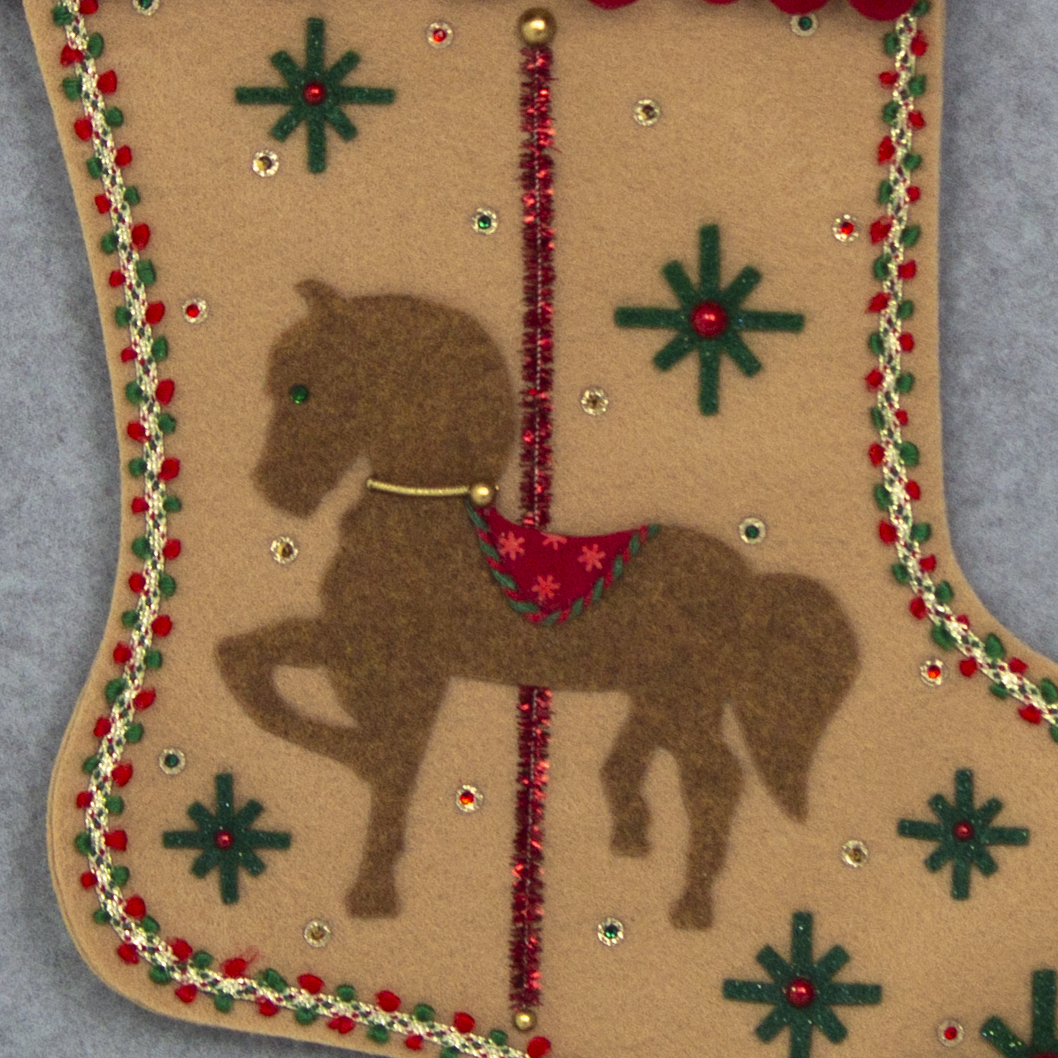 Copper felt horse on tan felt handmade Christmas stocking with pom poms, felt starbursts, tinsel pipe cleaner pole and decorated in red, dark green & gold. (front of Carousel Horse stocking - close up detail of horse).