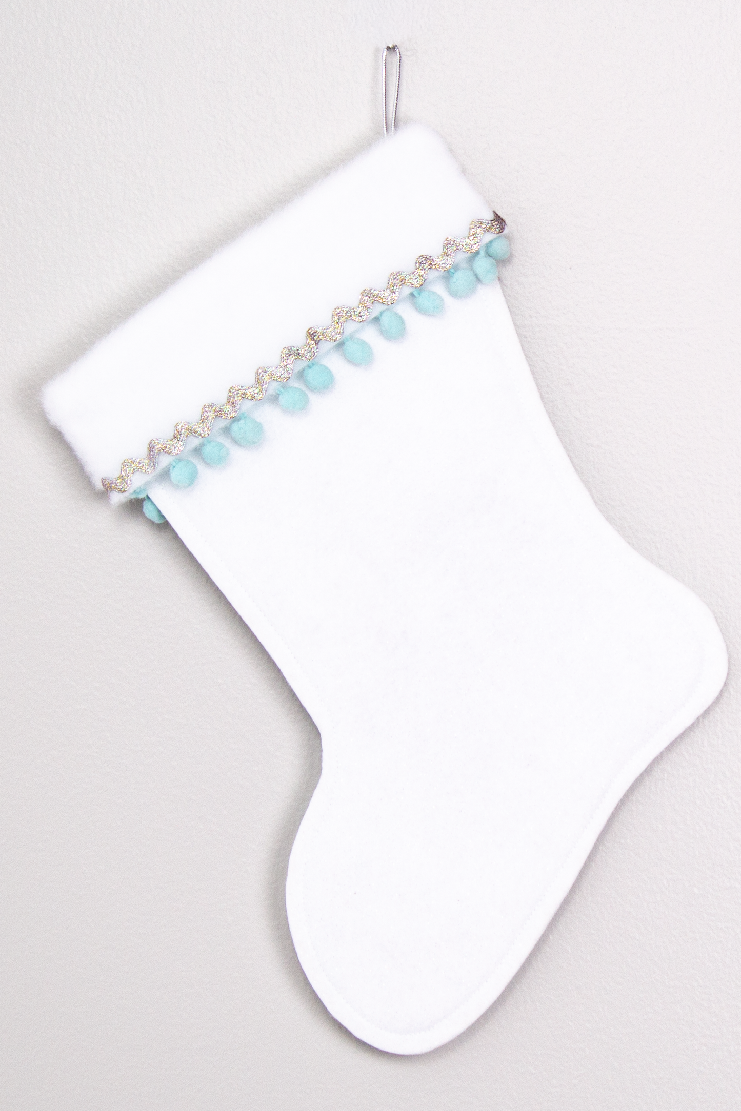 White glitter felt handmade Christmas stocking with pom poms and decorations in aqua & silver. (back of Carousel Unicorn stocking)