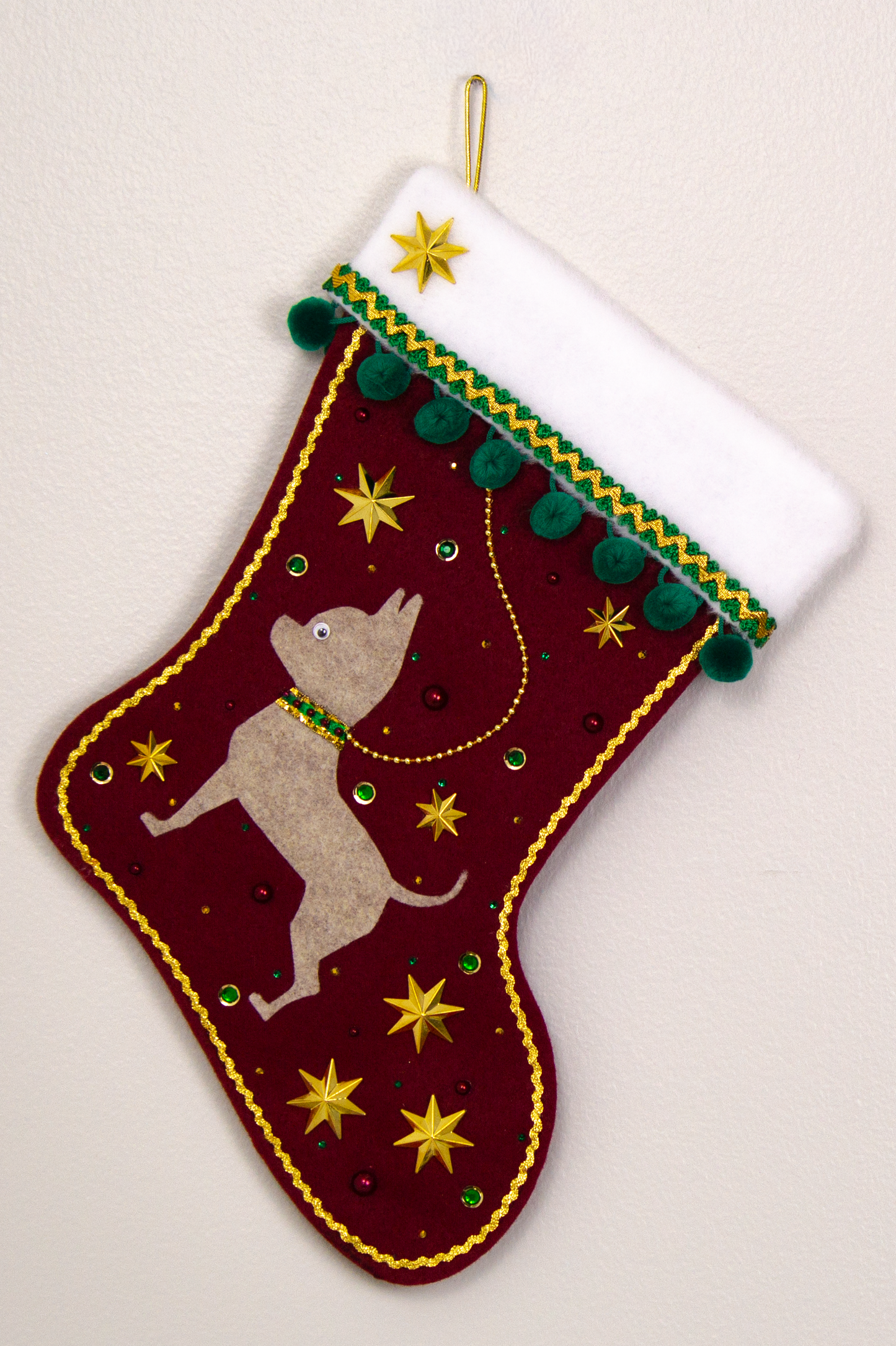 Sandstone short hair Chihuahua dog on ruby red felt handmade Christmas stocking with pom poms, stars and decorated in green, dark red and gold. (front of stocking)
