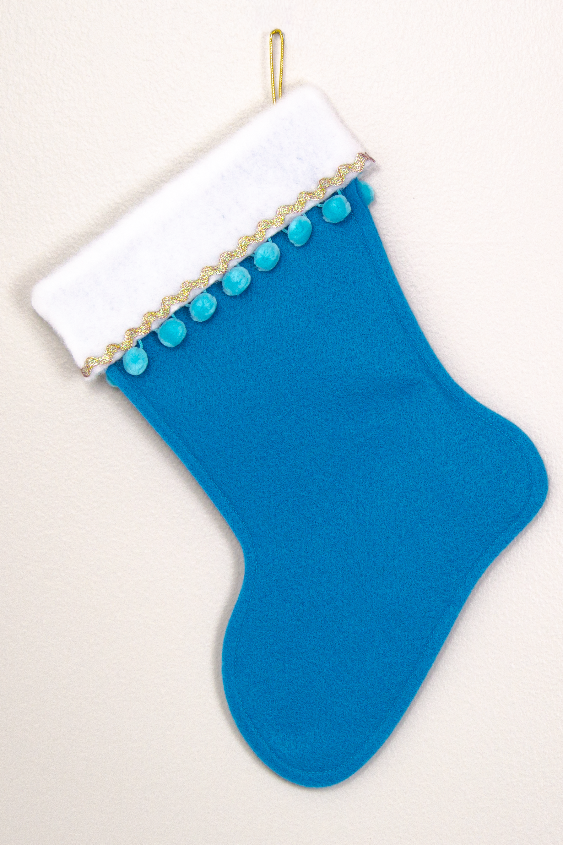 Peacock blue felt Christmas stocking with pom poms and decorations in blue and gold. (back of Chihuahua dog  stocking)