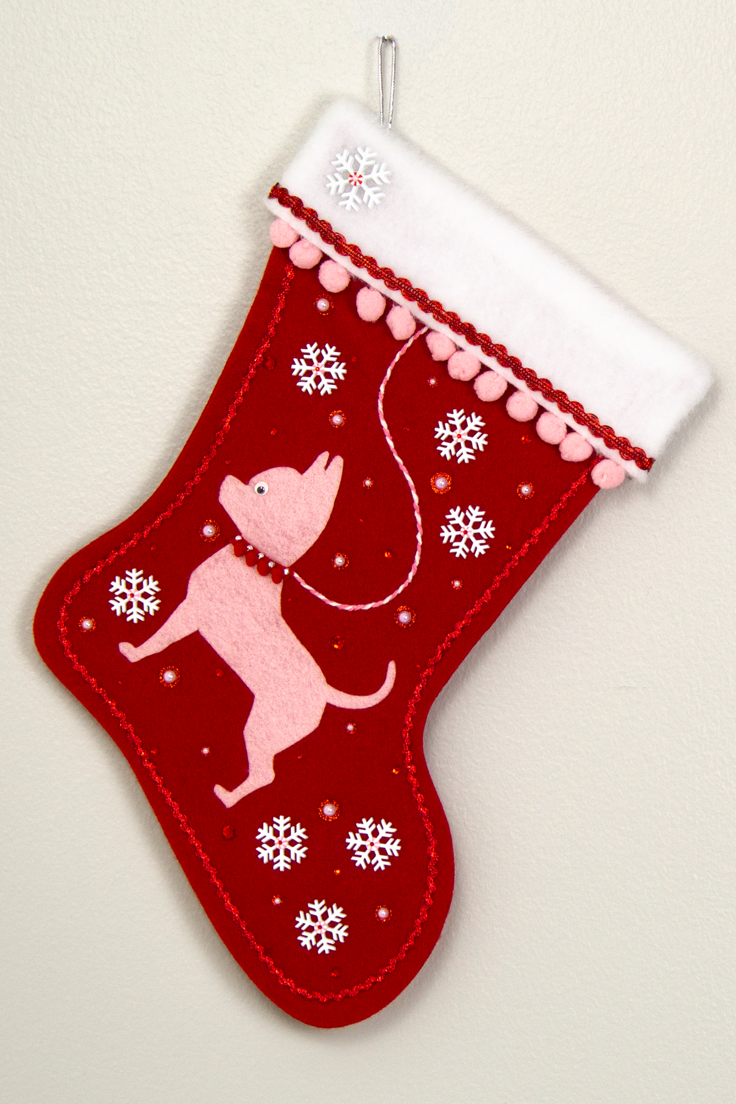 Light pink short hair Chihuahua dog felt Christmas stocking on red felt with snowflakes, pom poms and decorations in white, pink and red. (front of stocking)