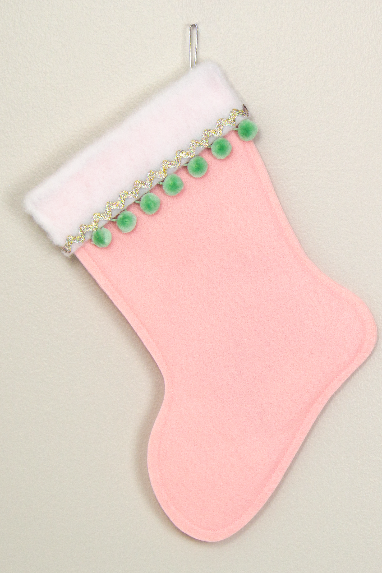 Light pink felt Christmas stocking with pom poms and decorations in mint green and silver. (back of long hair Chihuahua dog stocking)