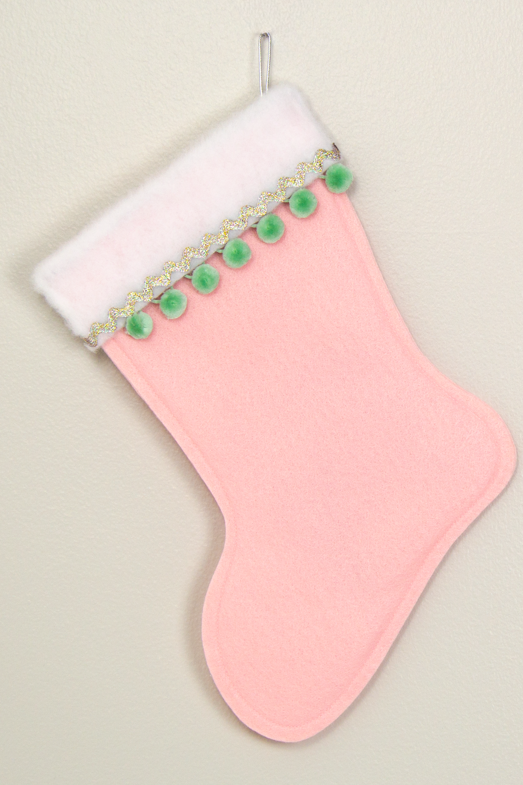Light pink felt Christmas stocking with pom poms and decorations in mint green and silver. (back of long hair Chihuahua dog stocking)
