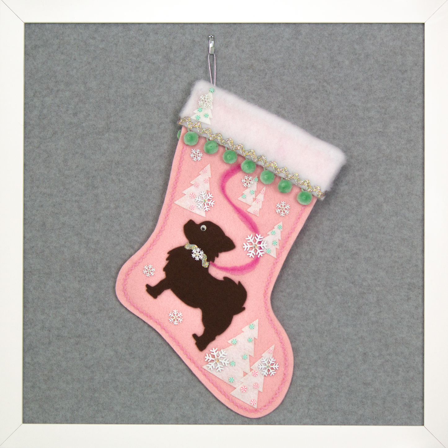 Chocolate brown long hair Chihuahua dog silhouette on a light pink felt Christmas stocking with pom poms, trees, snowflakes and decorations in mint green, pink, white and silver. (front of stocking)