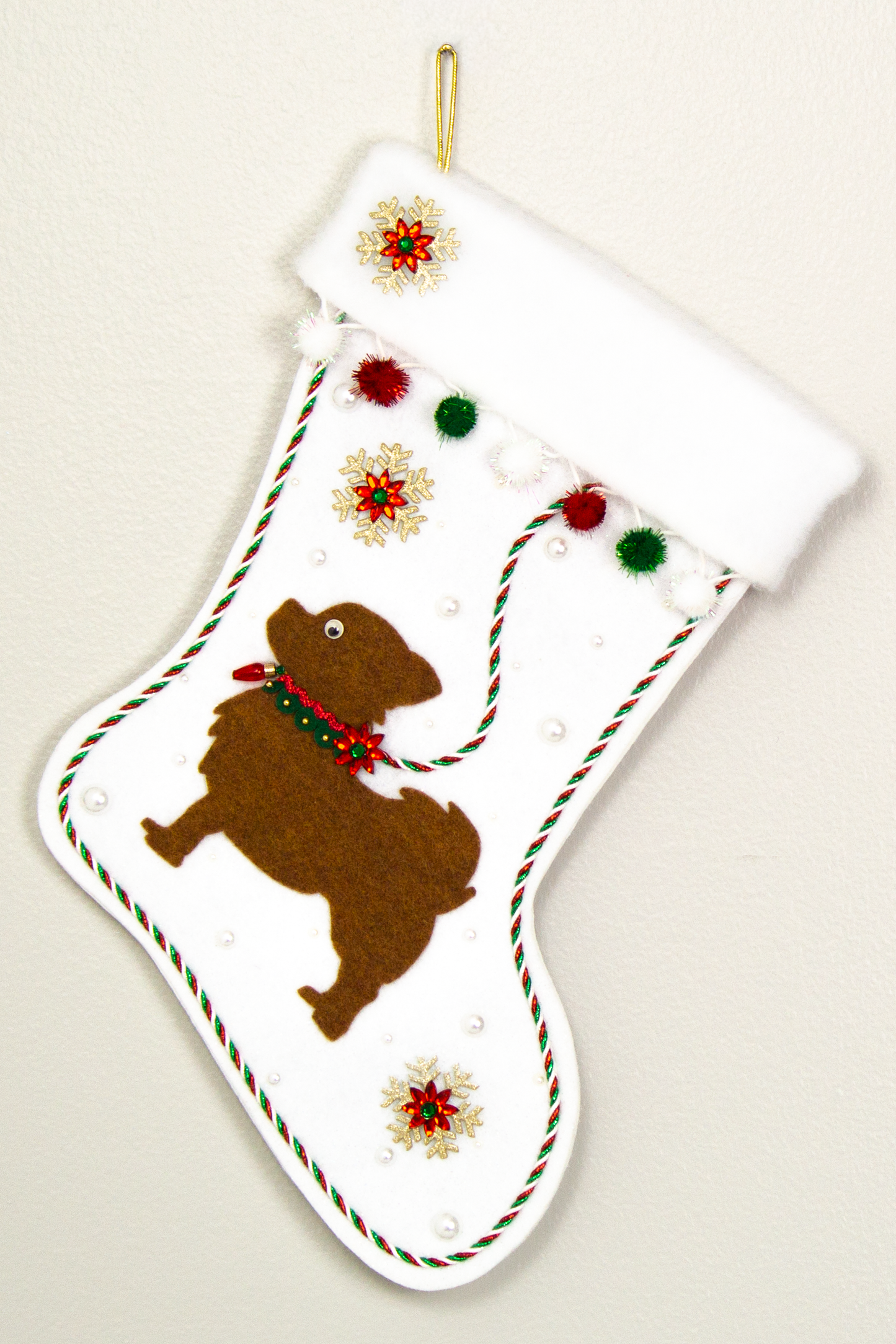 White glitter Christmas stocking with copper long hair Chihuahua small dog silhouette with sparkly pom poms, gold snowflakes, rhinestone poinsettias and decorations in green, red and gold. (front of stocking)