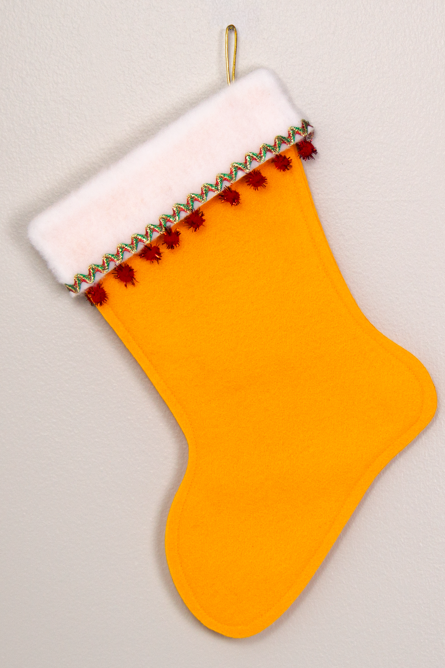 Gold felt handmade Christmas stocking with sparkly pom poms and decorations in green, red and gold. (back of Chihuahua dog stocking)