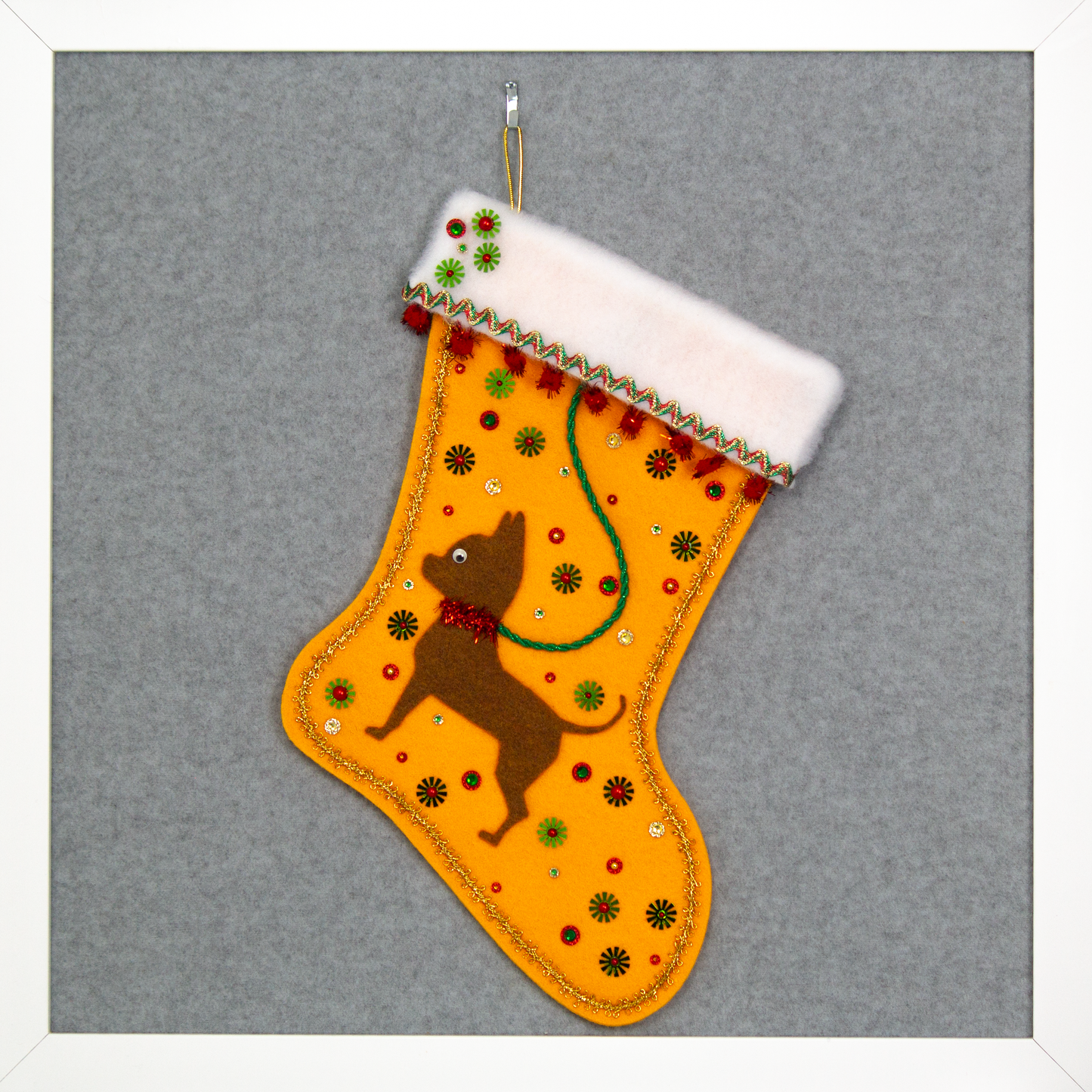 Copper short hair Chihuahua dog on Gold felt handmade Christmas stocking with sparkly pom poms, flower sequins and decorations in green, red and gold. (front of stocking)