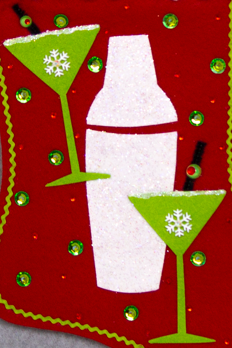 Glitter painted lime green martini glasses, chunky glitter painted white felt shaker on a holiday red felt handmade Christmas stocking with snowflake, pom poms, olive ribbon and decorated in green, red, white, black & silver. (front of stocking - close up detail of martini glasses & cocktail shaker)