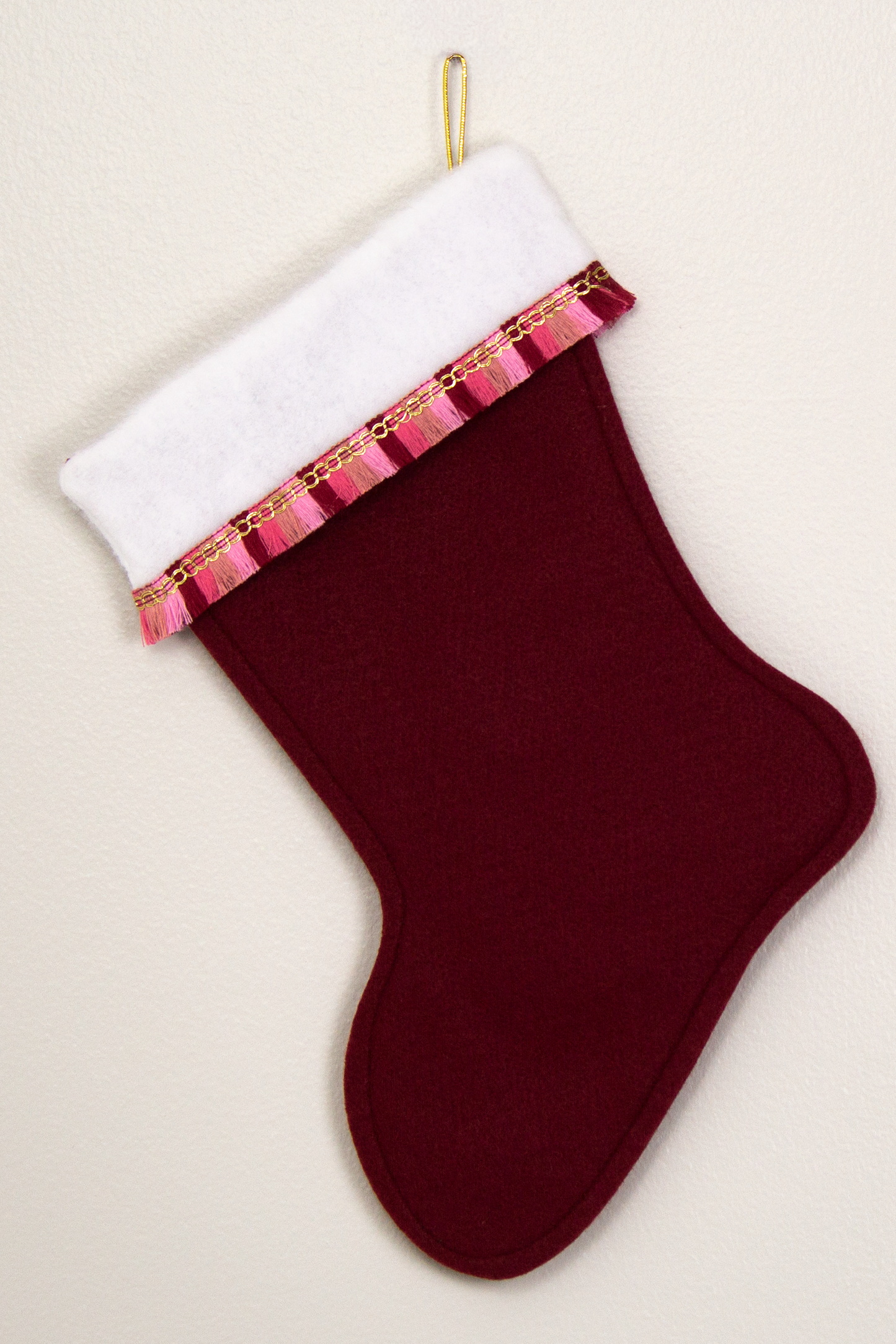 Ruby red felt Christmas stocking with fringe and decorations in gold, white and various pinks. (back of Corgi dog stocking)