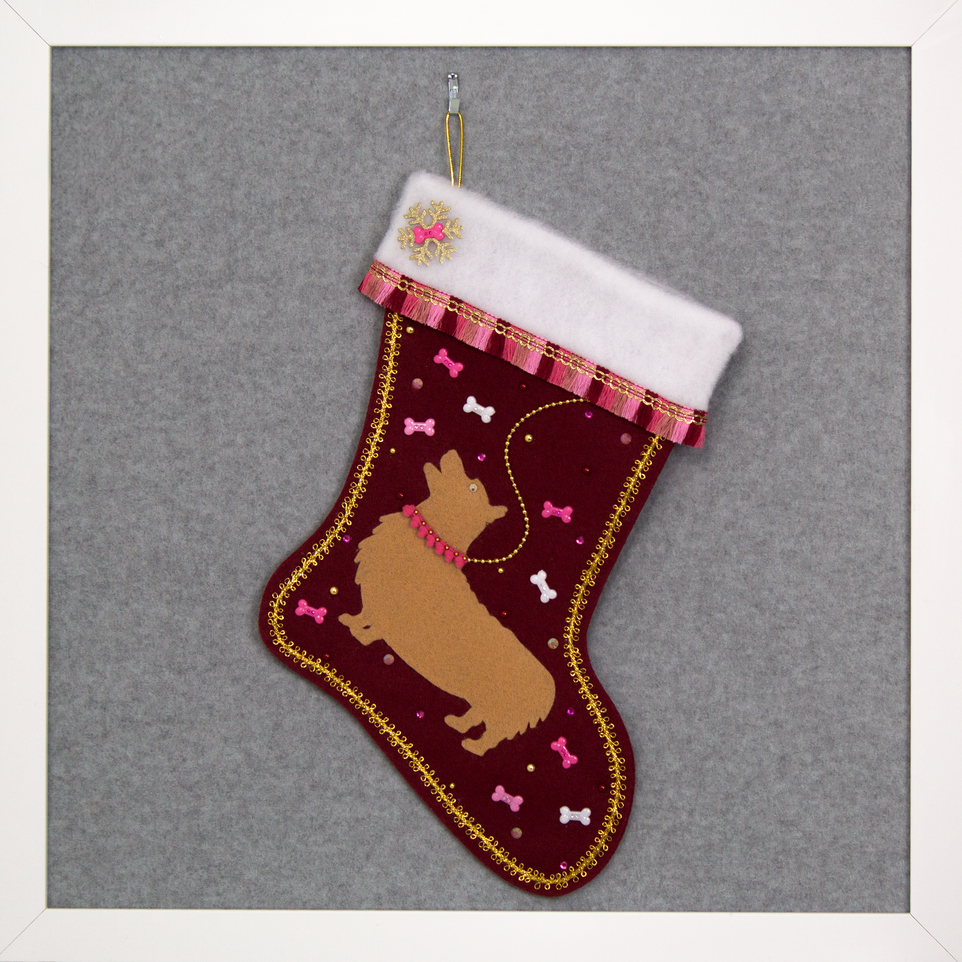 Tan Corgi dog on ruby red felt Christmas stocking with fringe, dog bones and decorations in gold, white and various pinks. (front of stocking)