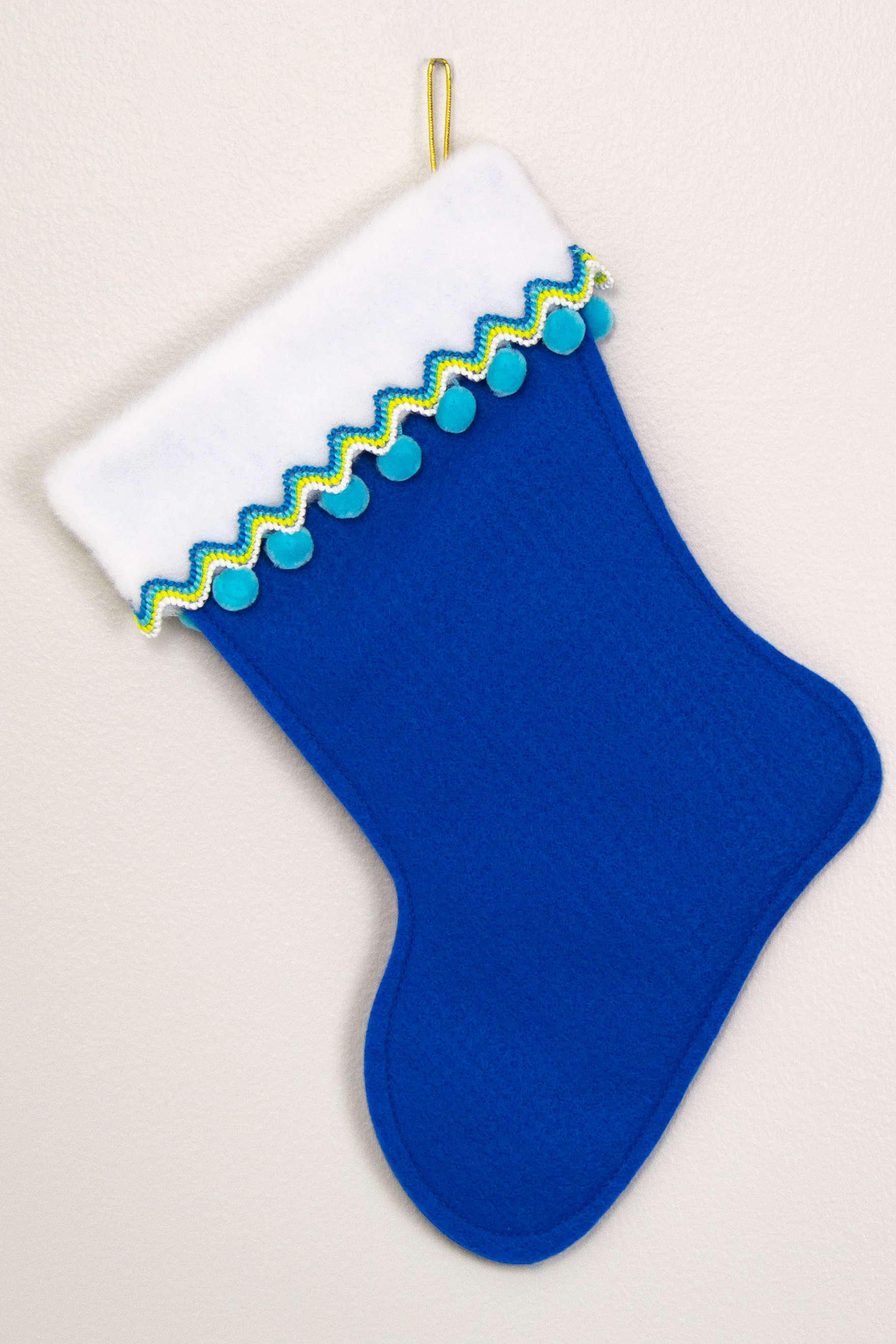 Royal blue felt Christmas stocking with pom poms and decorated in yellow, green, blues and gold. (back of Corgi dog stocking)