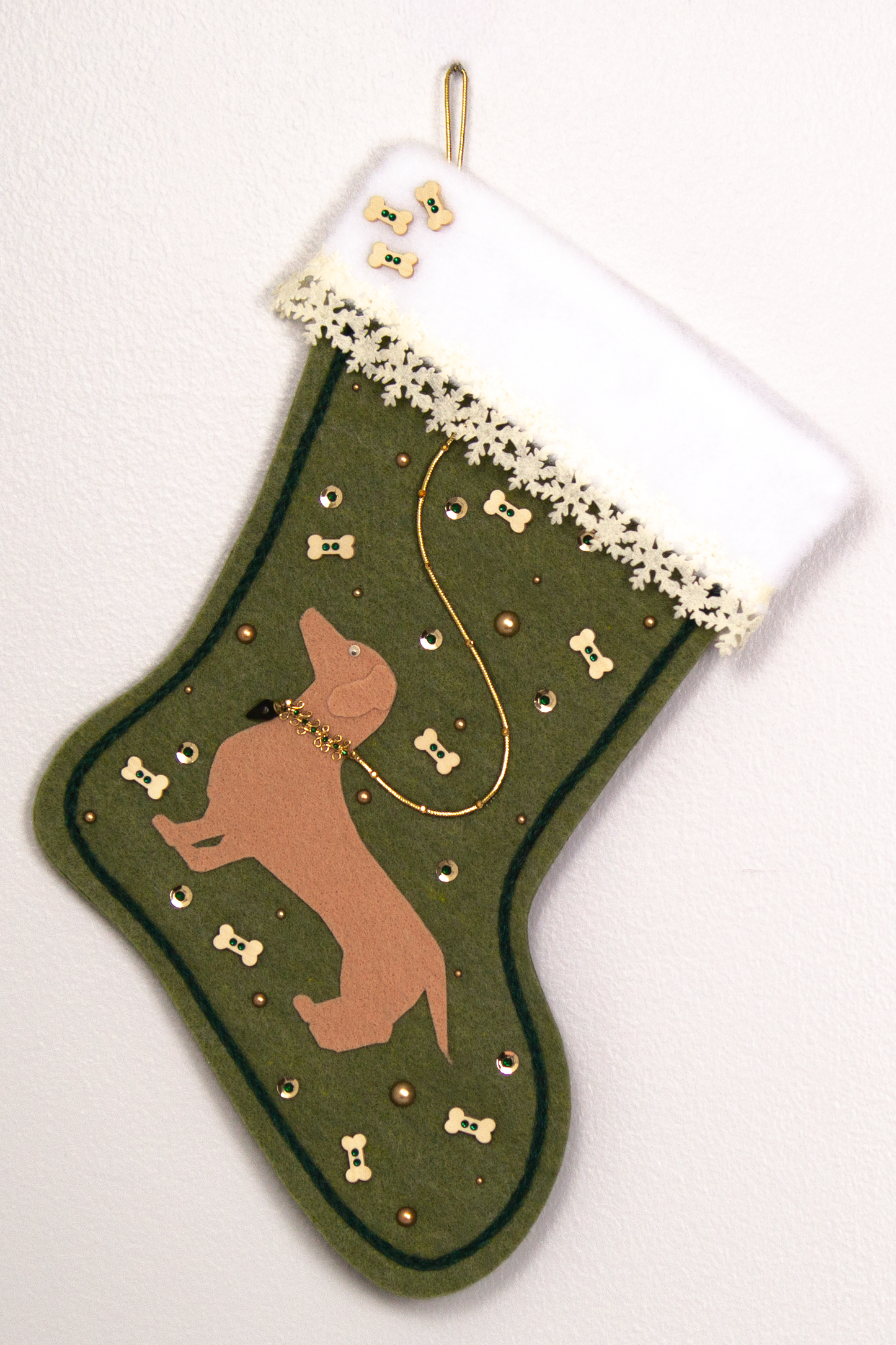 Tan Dachshund dog on olive green felt handmade Christmas stocking with laser cut felt snowflake trim, wood bone buttons and decoration in gold, cream and dark green. (front of stocking)