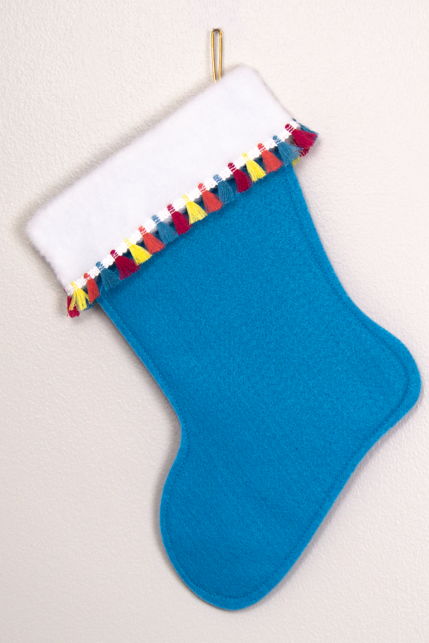 Peacock blue felt handmade Christmas stocking with multicolor fringe and decorated in white, blue, red, yellow, orange and gold. (back of Dachshund dog stocking)