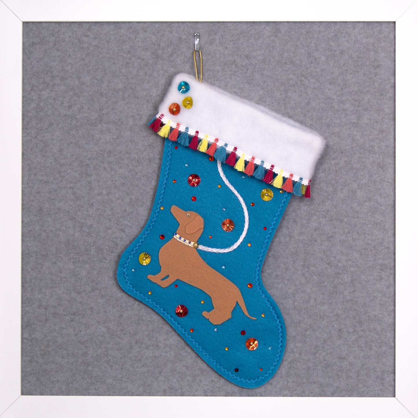 Tan Dachshund dog on peacock blue felt handmade Christmas stocking with multicolor fringe, sunburst sequins and decorated in white, blue, red, yellow, orange and gold. (front of stocking)