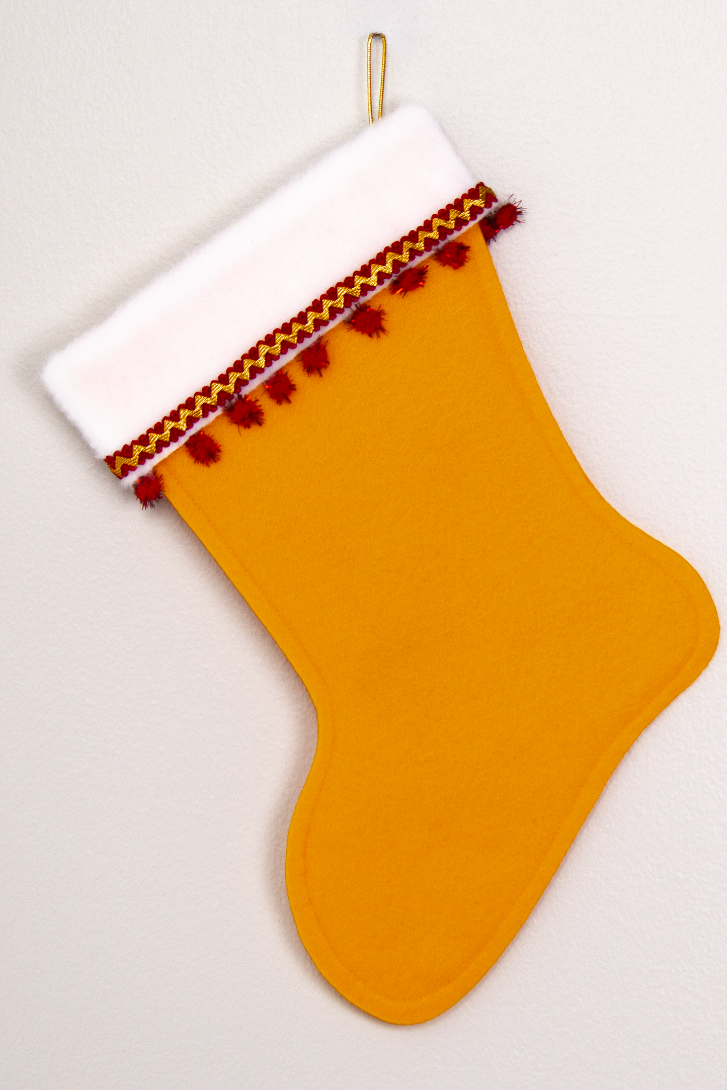Gold felt handmade Christmas stocking with sparkly pom poms and decorated in red & gold. (back of Dala horse stocking)