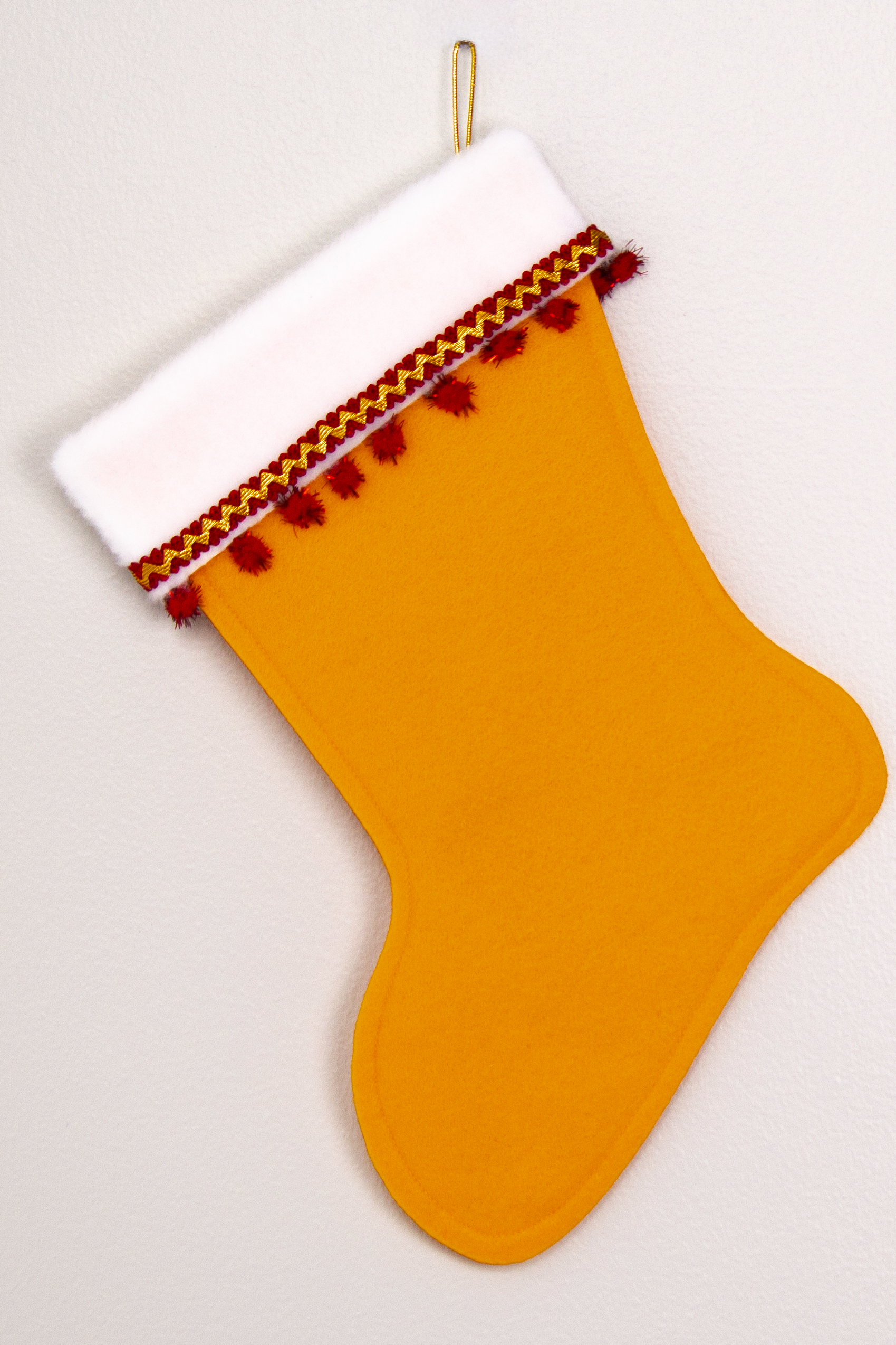 Gold felt handmade Christmas stocking with sparkly pom poms and decorated in red & gold. (back of Dala horse stocking)