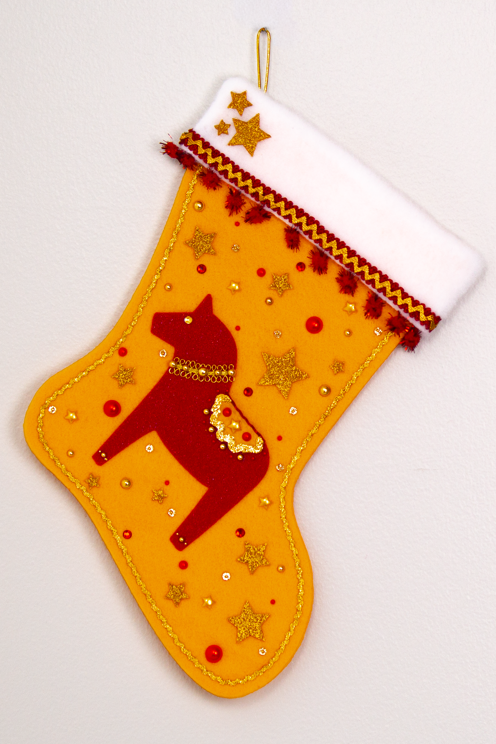 Red glitter Dala horse on gold felt handmade Christmas stocking with sparkly pom poms, gold glittered felt stars and decorated in red & gold. (front of stocking)