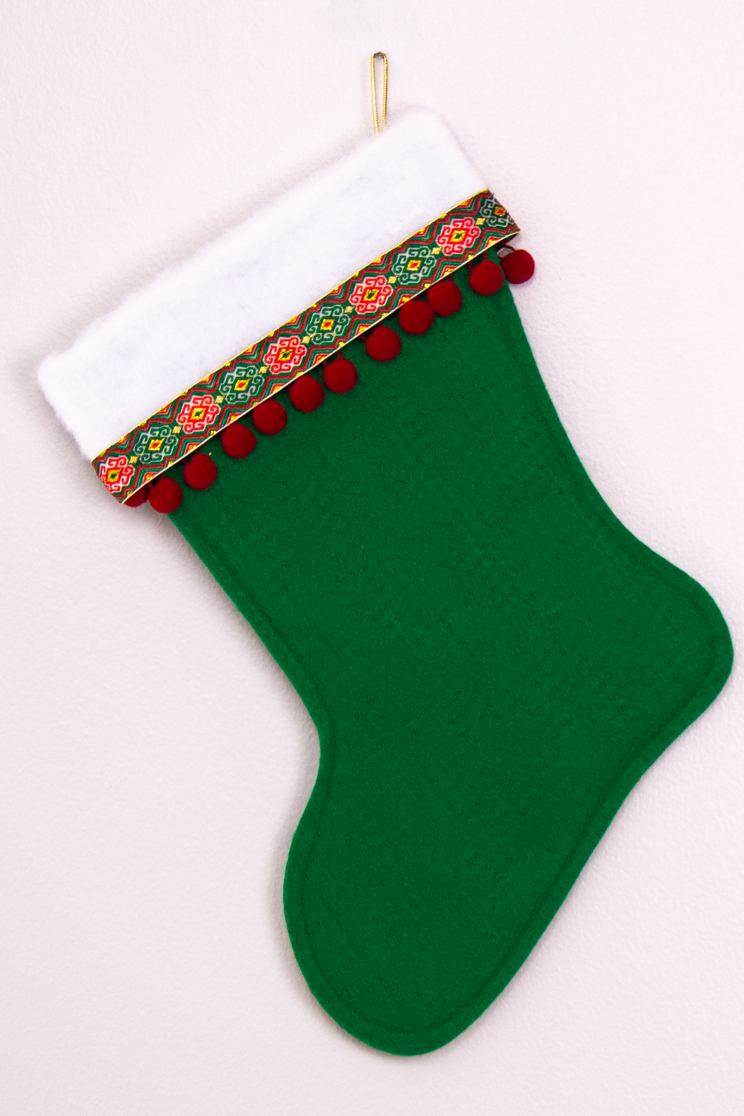 Holiday green felt handmade Christmas stocking with pom poms, decorative ribbon and decorated in gold, red & green. (back of Dala horse stocking)