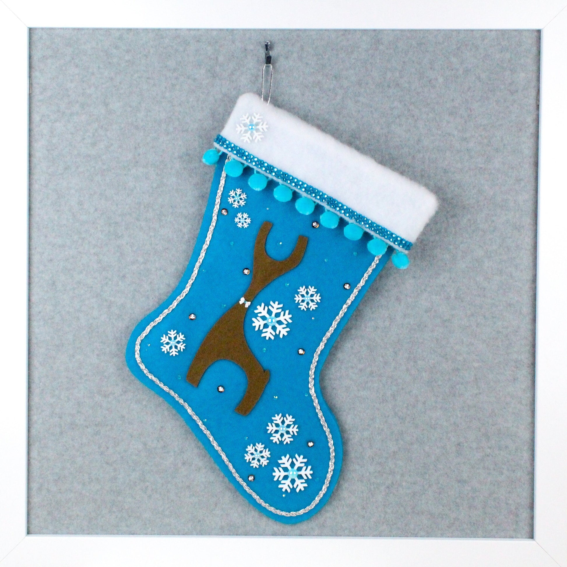 Brown Danish reindeer on peacock blue felt one of a kind handmade Christmas stocking with white snowflakes, blue pom poms and silver decorations.