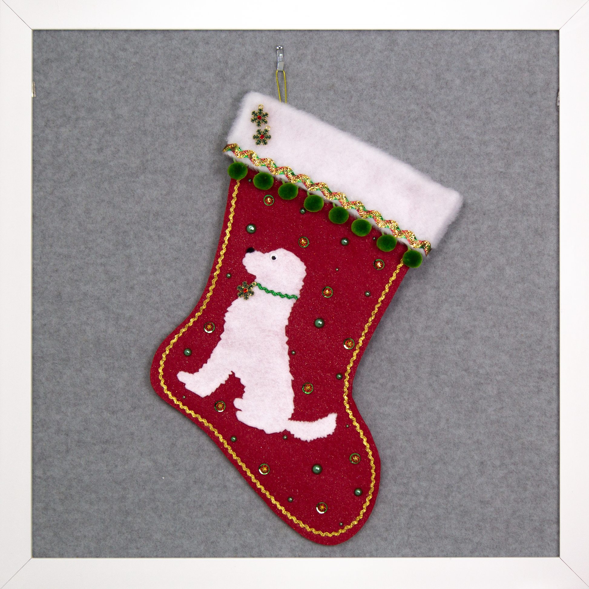 White labradoodle dog on red glitter felt Christmas stocking with green and gold decorations.
