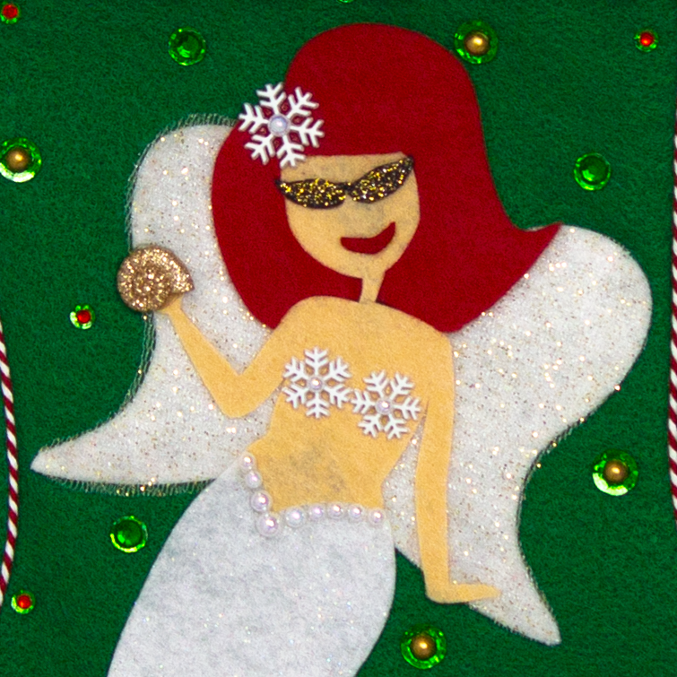 Ethel Mermaid with red hair, white glitter fin/tail, wings in white & gold mesh,  holding a sparkly seashell button, and a "bra" made of snowflake buttons on a holiday green felt handmade Christmas stocking decorated in white, red, green & gold. (front of stocking - close up detail of mermaid)