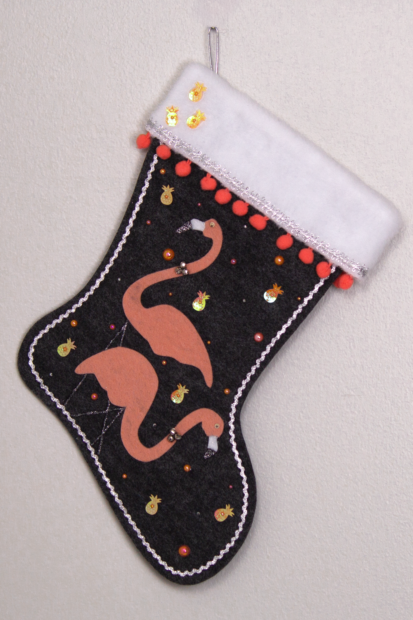Coral flamingos on charcoal gray felt handmade Christmas stocking with pom poms, pineapple sequins and decorated in coral, black & silver. (front of stocking)