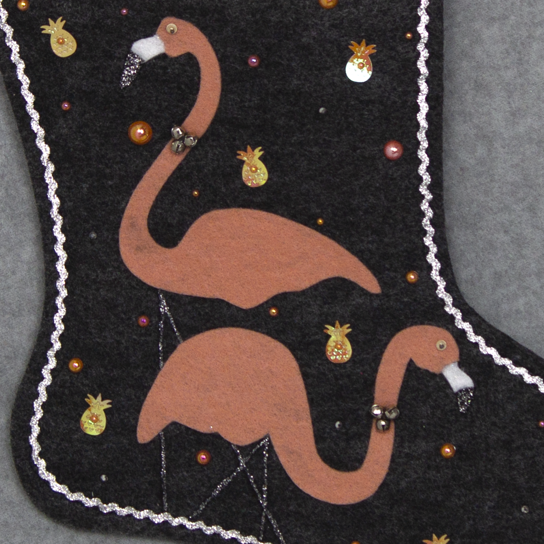 Coral flamingos on charcoal gray felt handmade Christmas stocking with pom poms, pineapple sequins and decorated in coral, black & silver. (front of stocking - close up detail of flamingos)