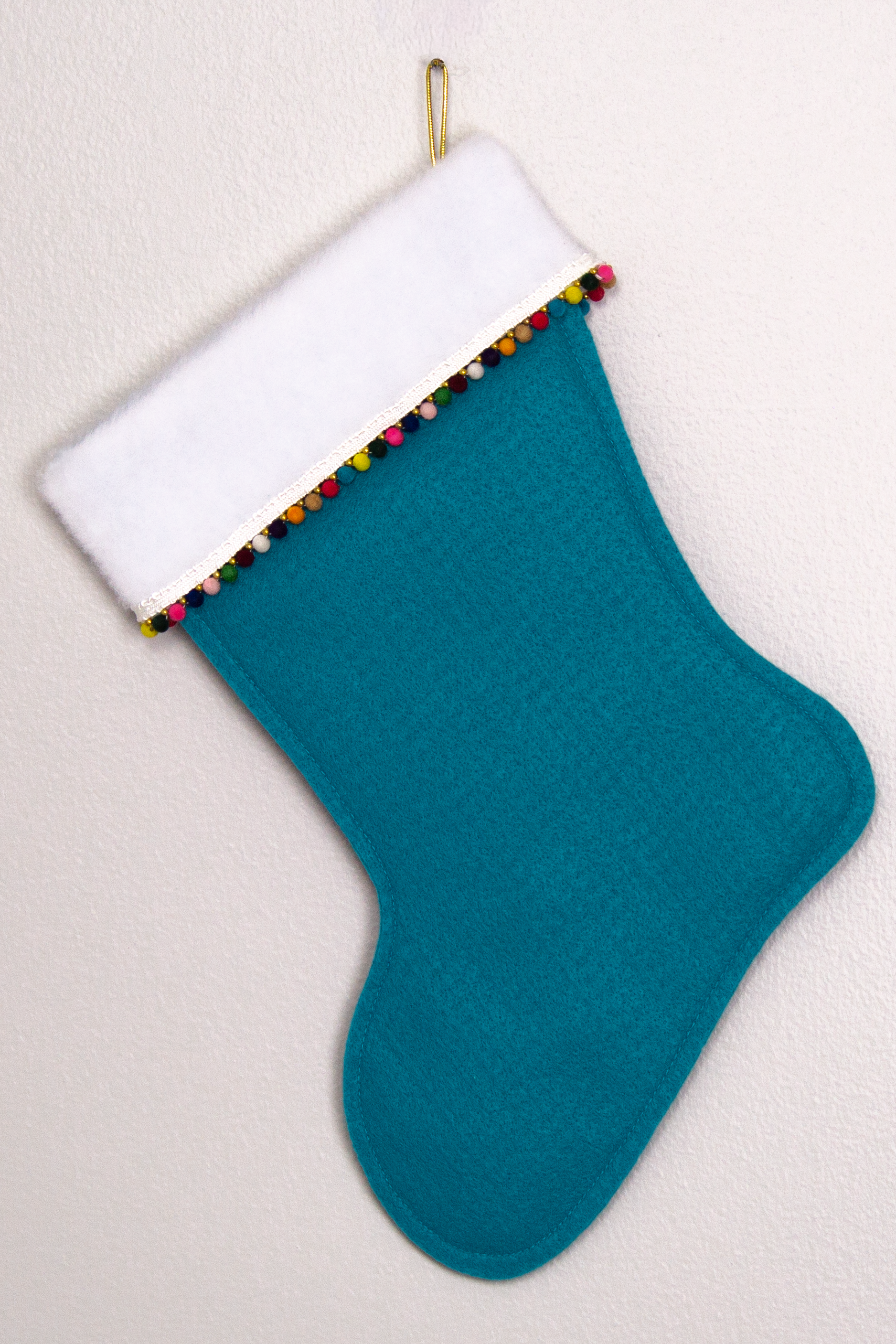 Turquoise felt handmade Christmas stocking with mini pom pomsand decorated in gold & multicolors. (back of Flamingo stocking)