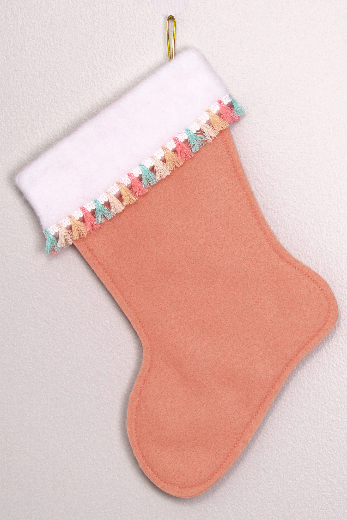 Coral felt handmade Christmas stocking with tassel fringe and decorated in gold & pastel colors. (back of Flamingo stocking)