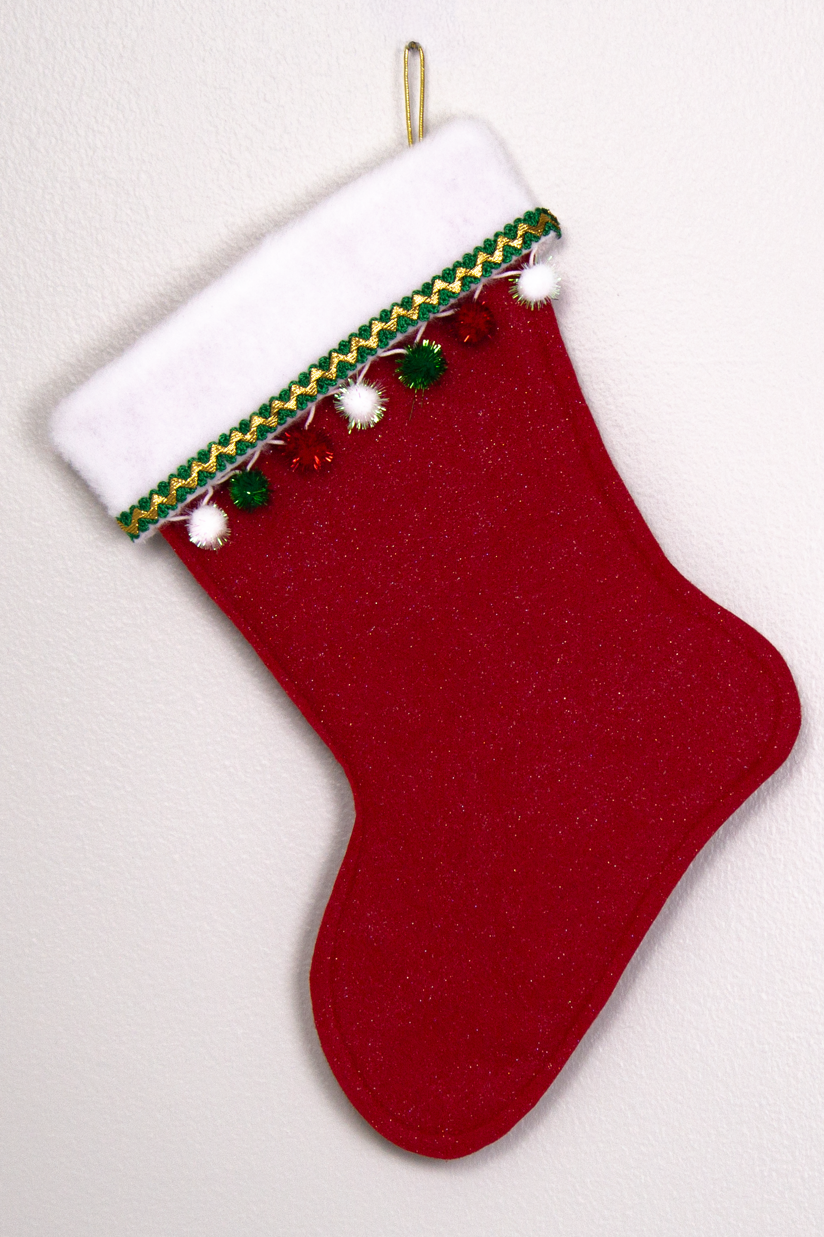Red glitter felt handmade Christmas stocking with sparkly pom poms and decorated in red, green, white and gold. (back of German Shepherd dog stocking)