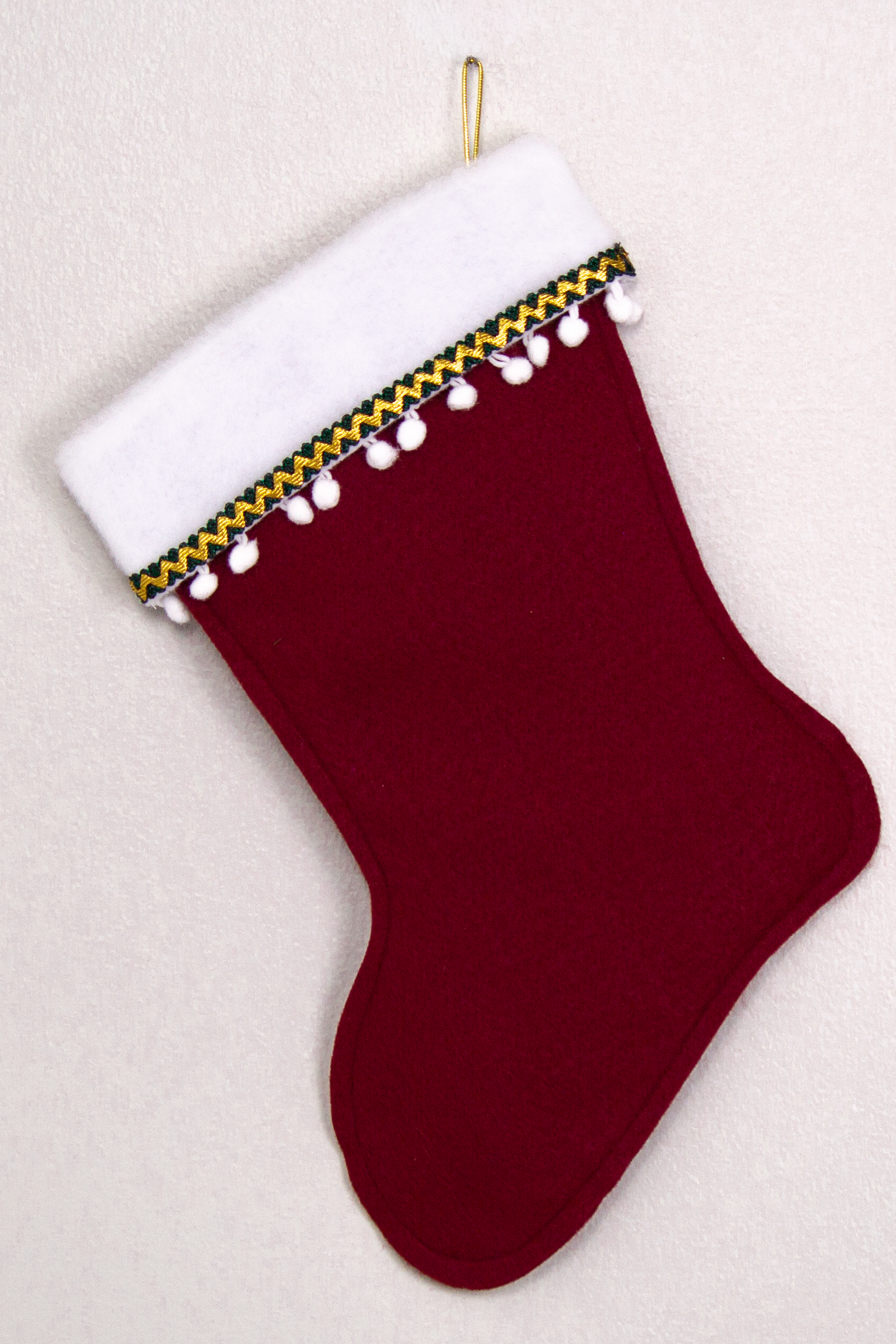 Ruby red felt handmade Christmas stocking with pom poms and decorated in white, green, red & gold. (back of Gingerbread stocking)
