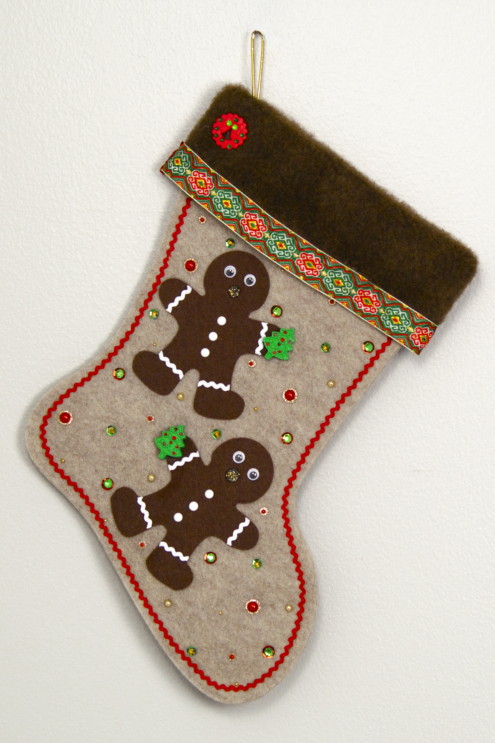 Twin dark brown Gingerbread men on sandstone beige felt handmade Christmas stocking with brown fur trim, decorative ribbon, tree buttons, a wreath button and decorated in red, green, white & gold. (front of stocking)