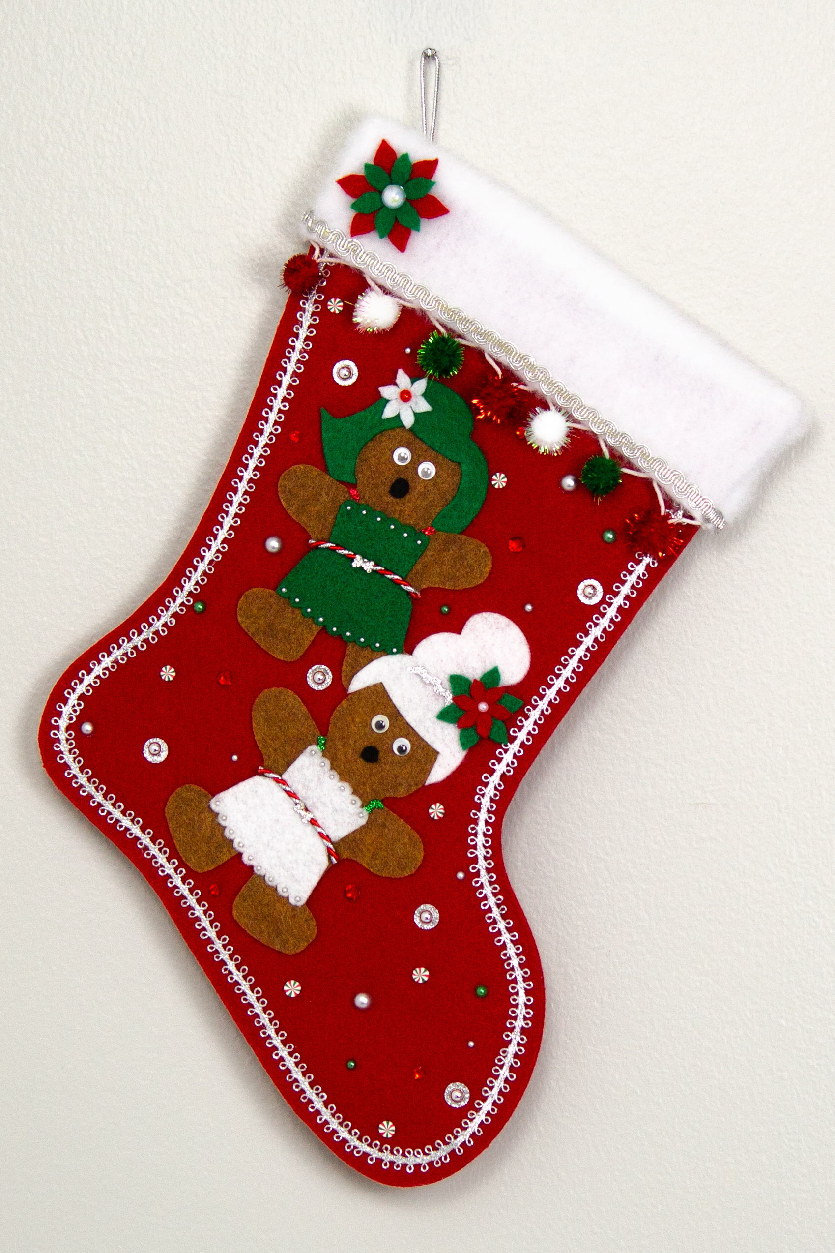 Twin copper felt Gingerbread on a holiday red felt handmade Christmas stocking with sparkly pom poms, felt poinsettias and decorated in white, green, red & silver. (front of stocking)