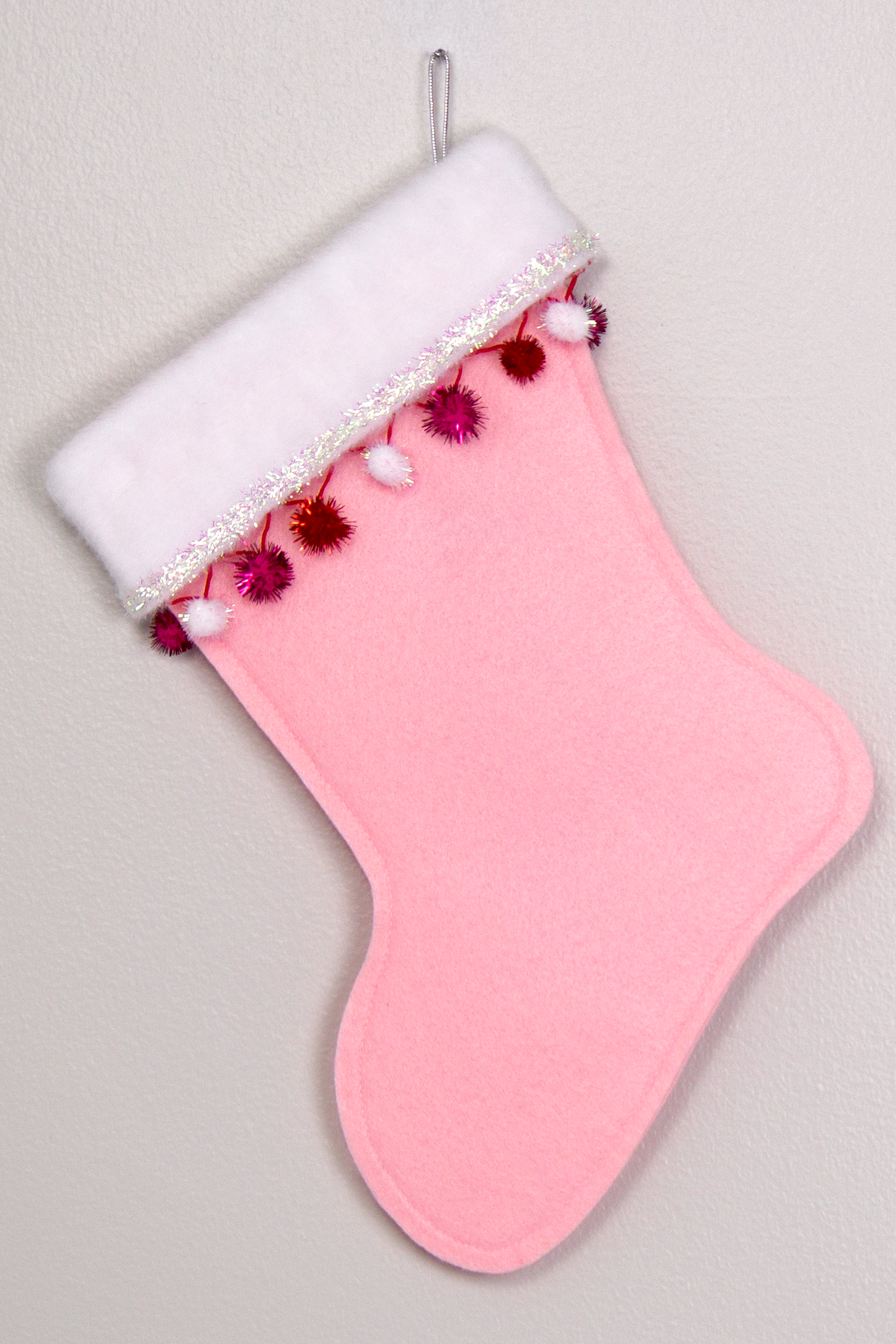 Light pink felt handmade Christmas stocking with sparkly pom poms, tinsel and decorated in red, pinks, white and silver. (back of Great Dane dog stocking)