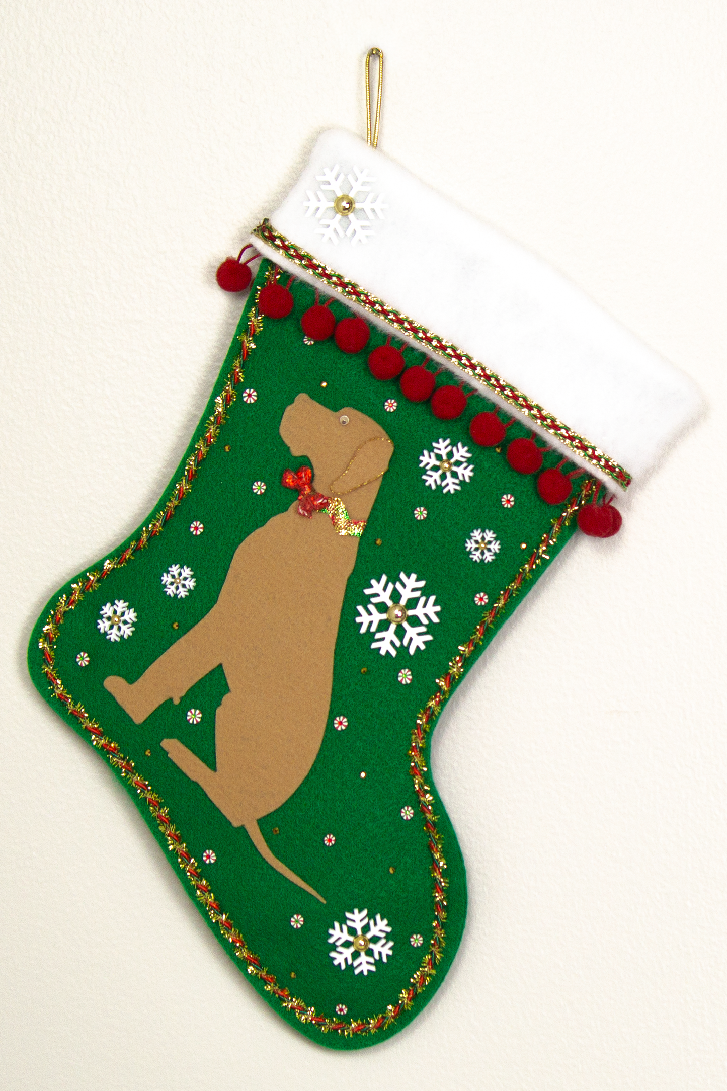 Tan Great Dane dog on holiday green felt handmade Christmas stocking with snowflakes, pom poms and decorated in white, green, red and gold. (front of stocking)