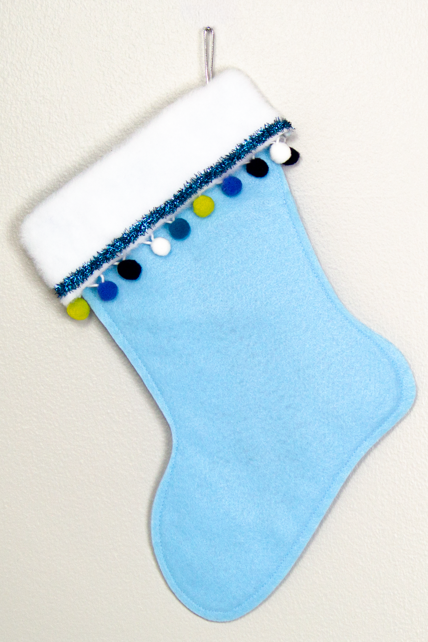 Light blue felt handmade Christmas stocking with pom poms, tinsel and decorated in white, blues, green and silver. (back of Great Dane dog stocking)