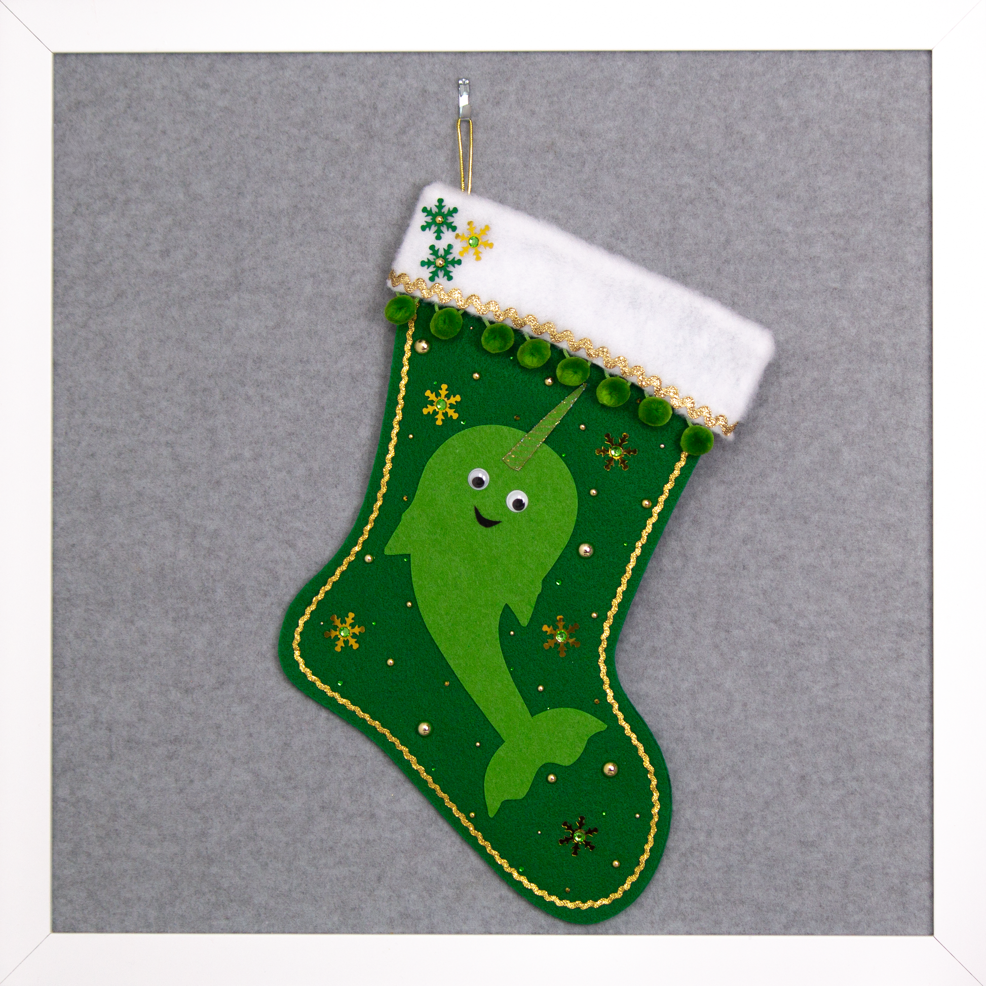 Bright green Narwhal on a holiday green felt handmade Christmas stocking with pom poms, googlie eyes, sequin snowflakes and decoration green & gold. (front of stocking)