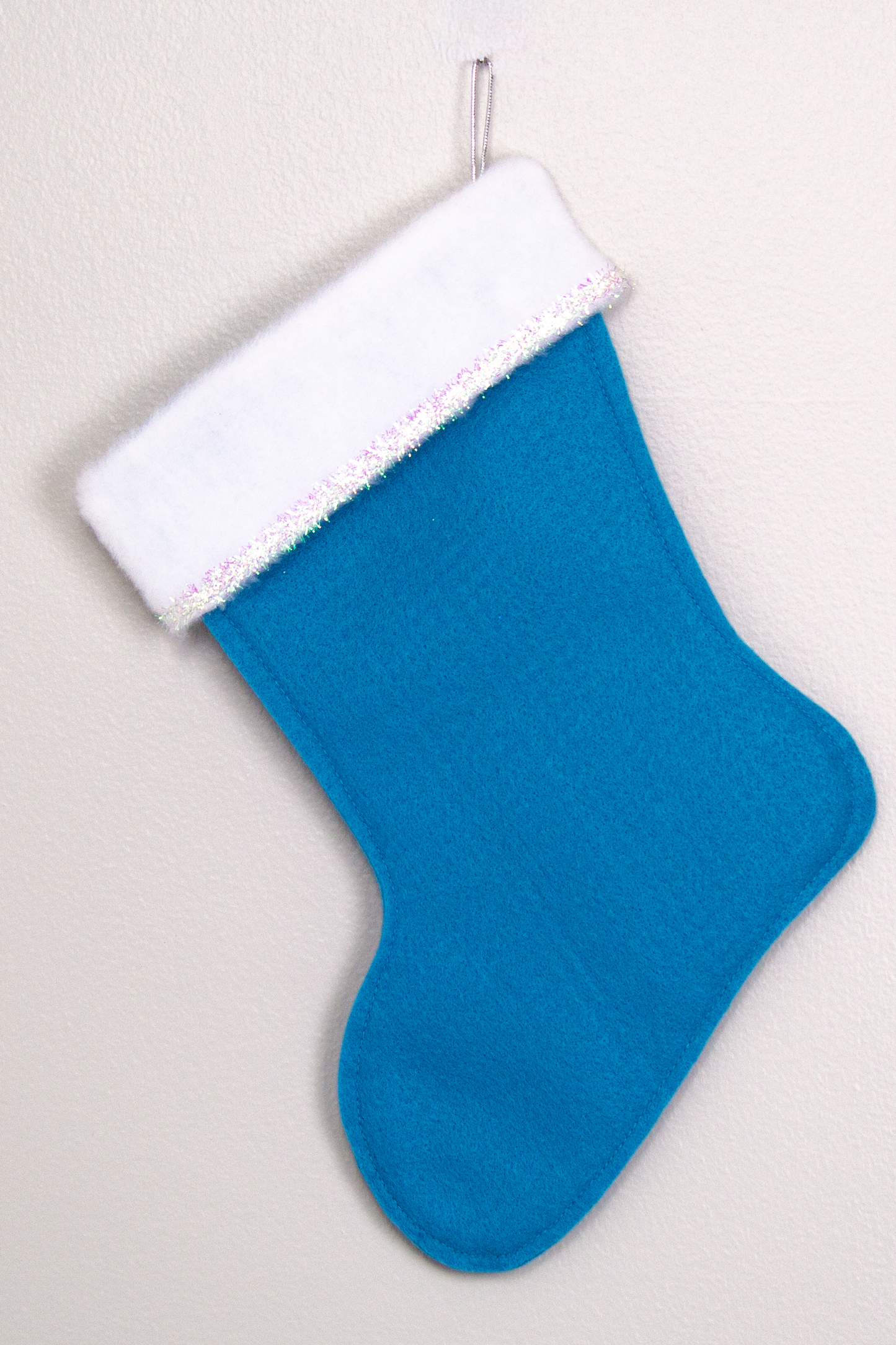 Peacock blue felt handmade Christmas stocking with tinsel ribbon and decoration in clear & silver. (back of Narwhal stocking)