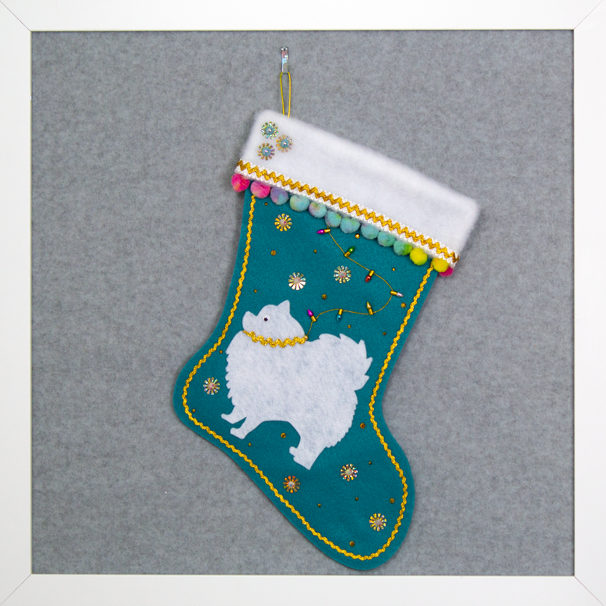 White Pomeranian Pom dog on turquoise felt handmade one of a kind Christmas stocking with gold and rainbow colored decorations.