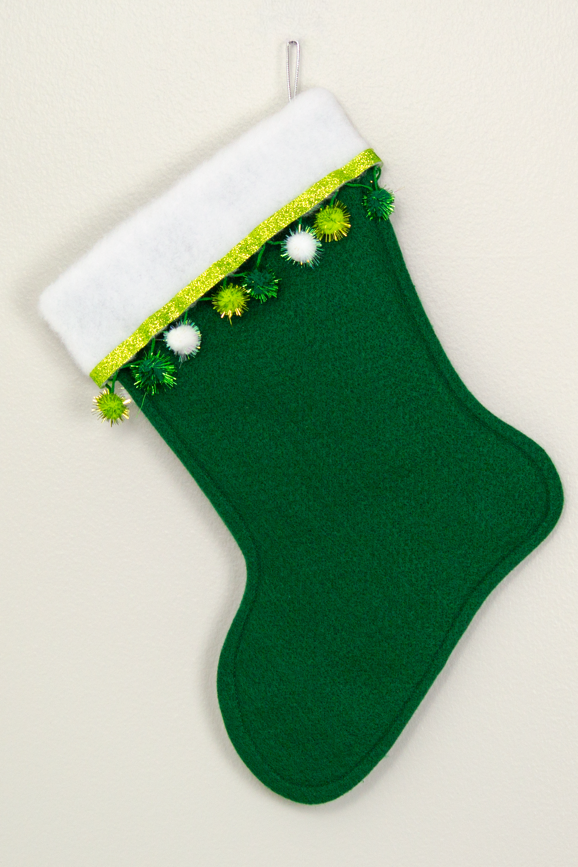 Back of green Christmas stocking with white poodle design