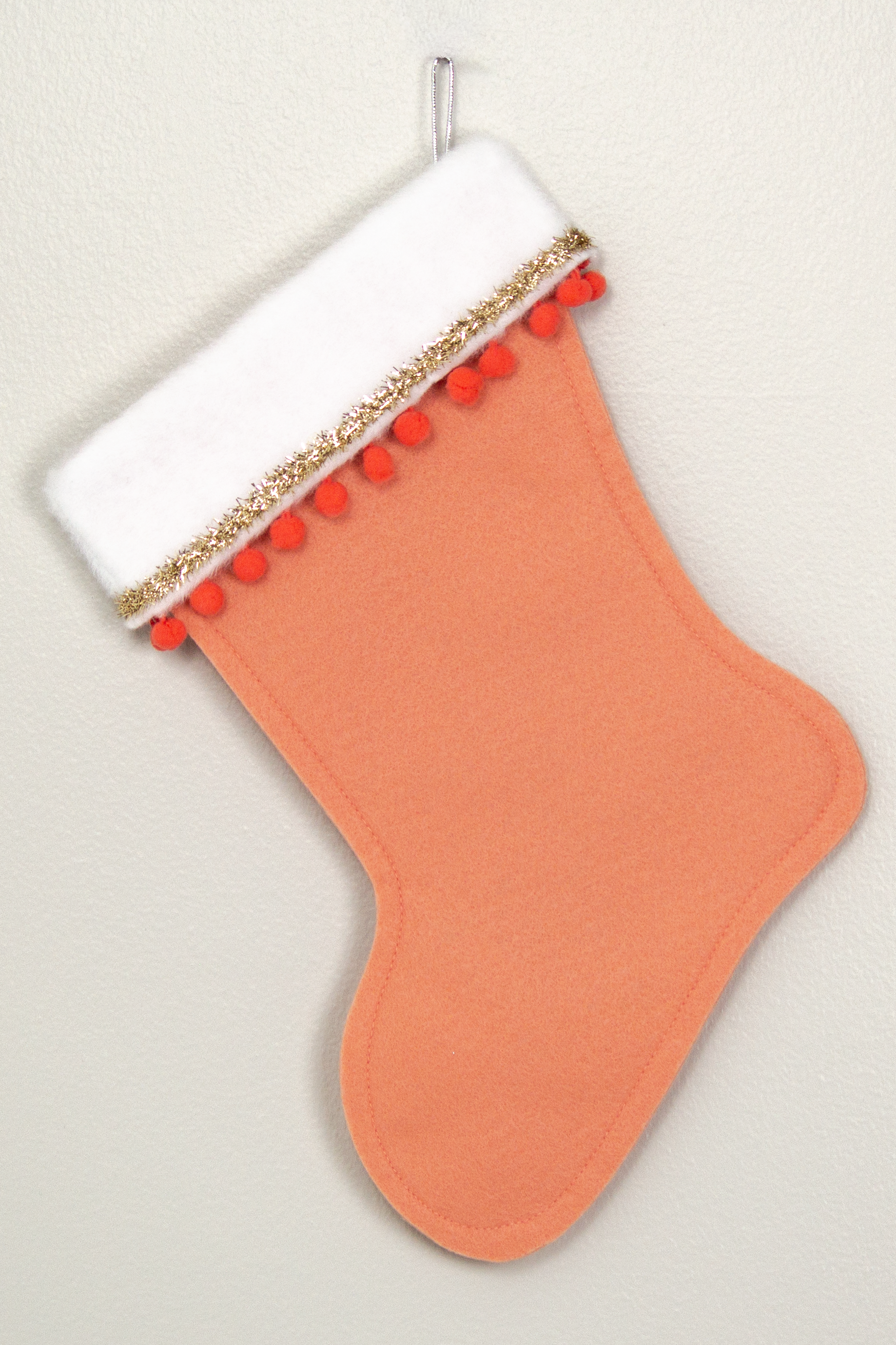 Back of decorative Christmas stocking with a copper poodle on coral felt with gold accents.