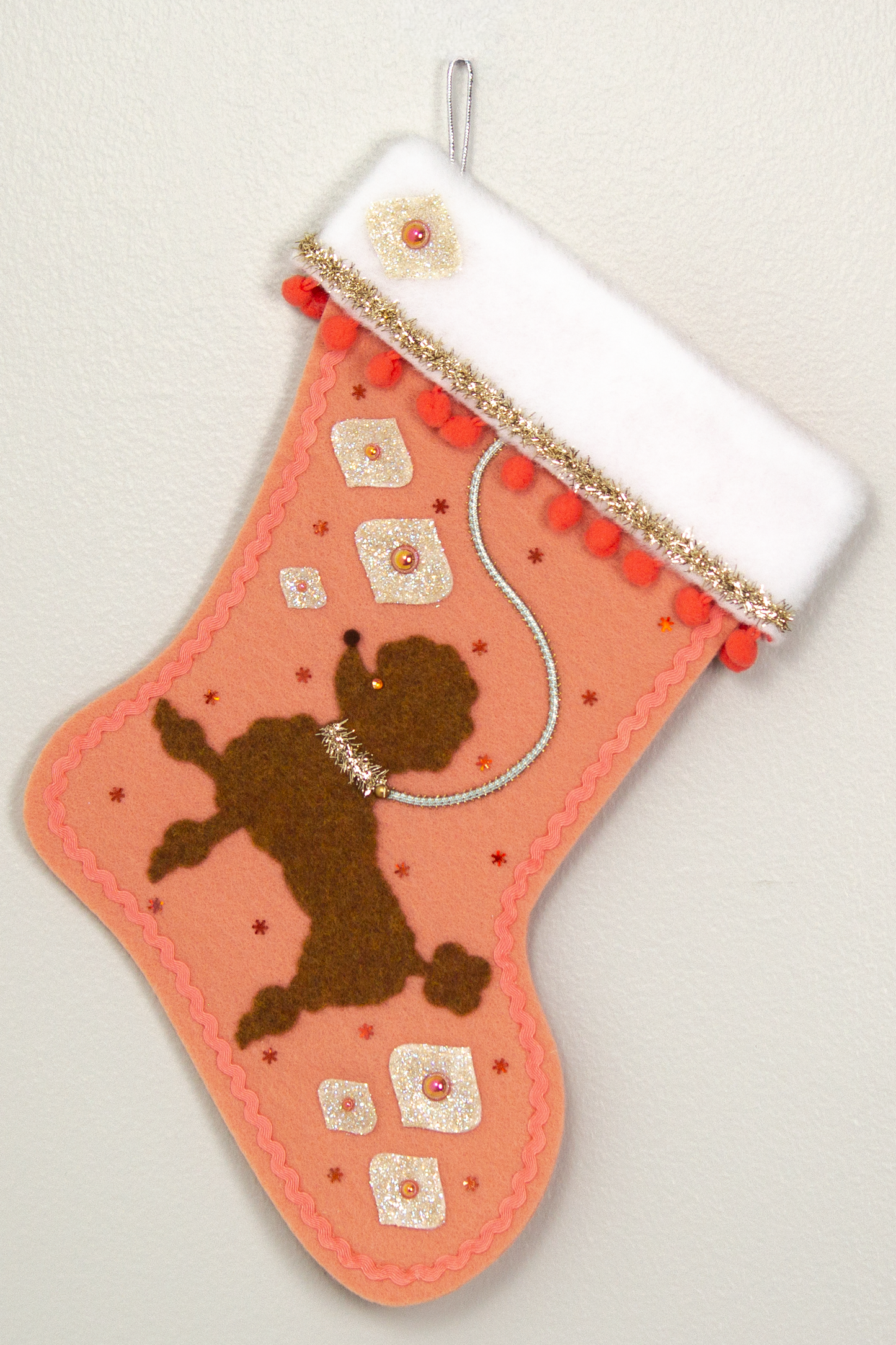 Decorative Christmas stocking with a copper poodle on coral felt with gold accents.