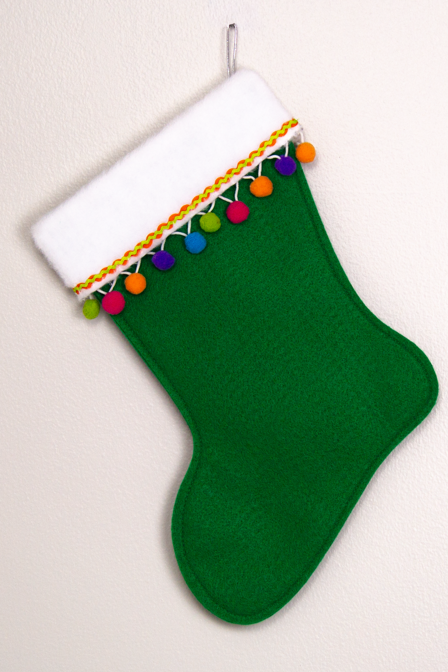 Holiday green felt handmade Christmas stocking with pom poms and decorated in orange, purple, blue, greens, hot pink & silver. (back of marquise shaped Santa  stocking)