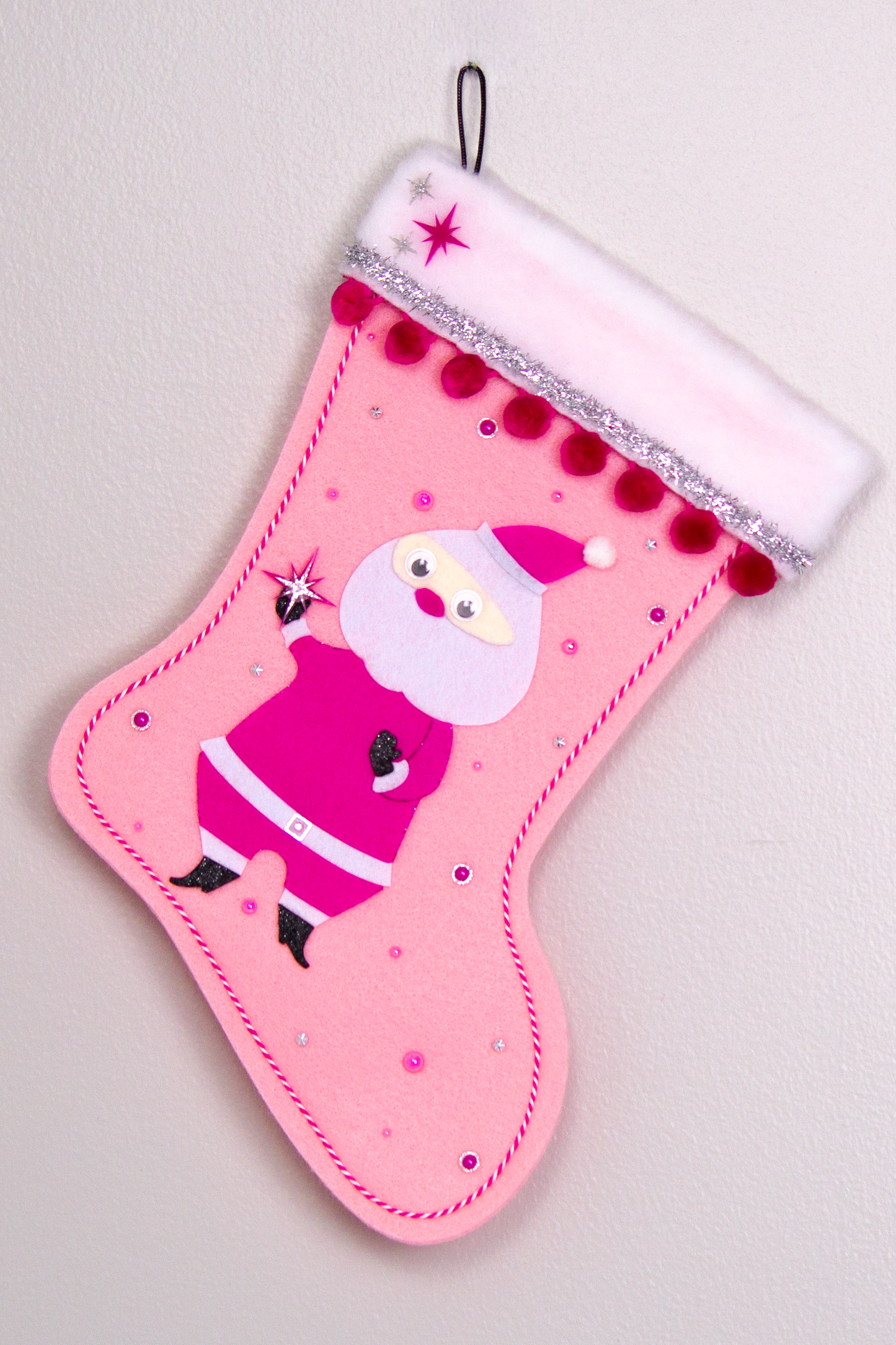 Retro Santa in hot pink suit on light pink felt handmade Christmas stocking with pom poms, tinsel ribbon and decorated in black, pinks & silver. (front of stocking)