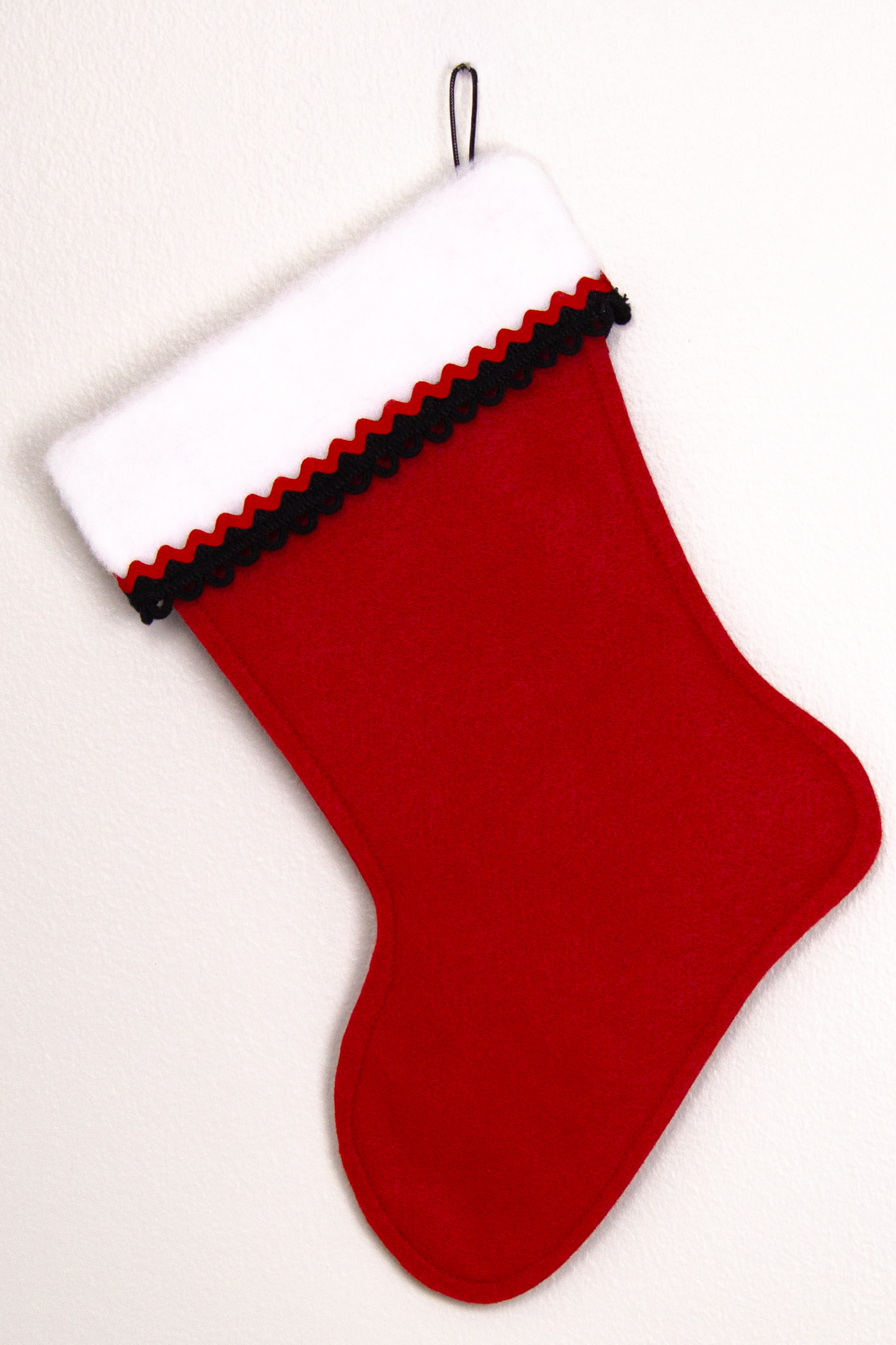 Holiday red felt handmade Christmas stocking decorated in black and red. (back of Santa stocking)