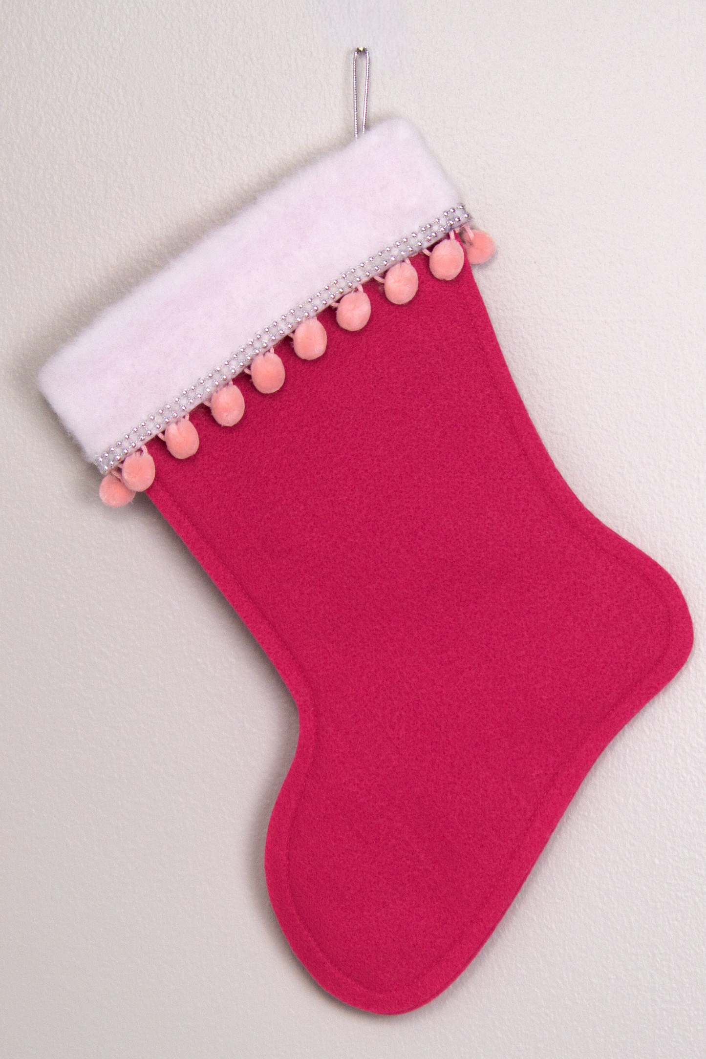 Bright pink felt handmade Christmas stocking with pom poms and decoration in pink & silver. (back of triangle Santa stocking)
