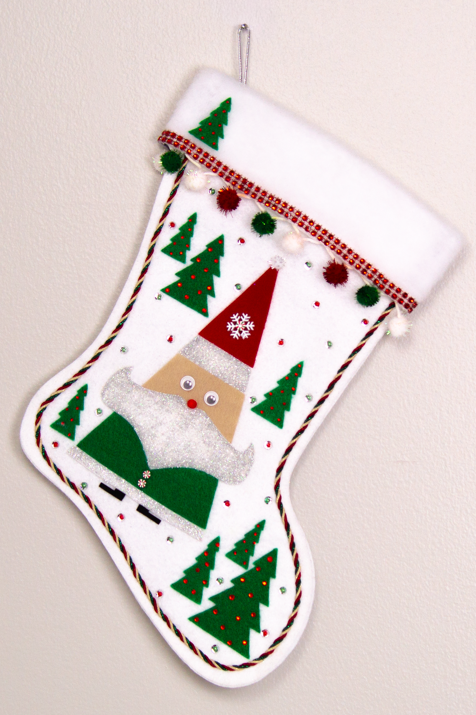 Triangular Santa (Holt Howard for Libbey inspired) in green suit and red hat on white glitter felt handmade Christmas stocking with trees, sparkly pom poms and decoration in red, green, white & silver. (front of stocking)