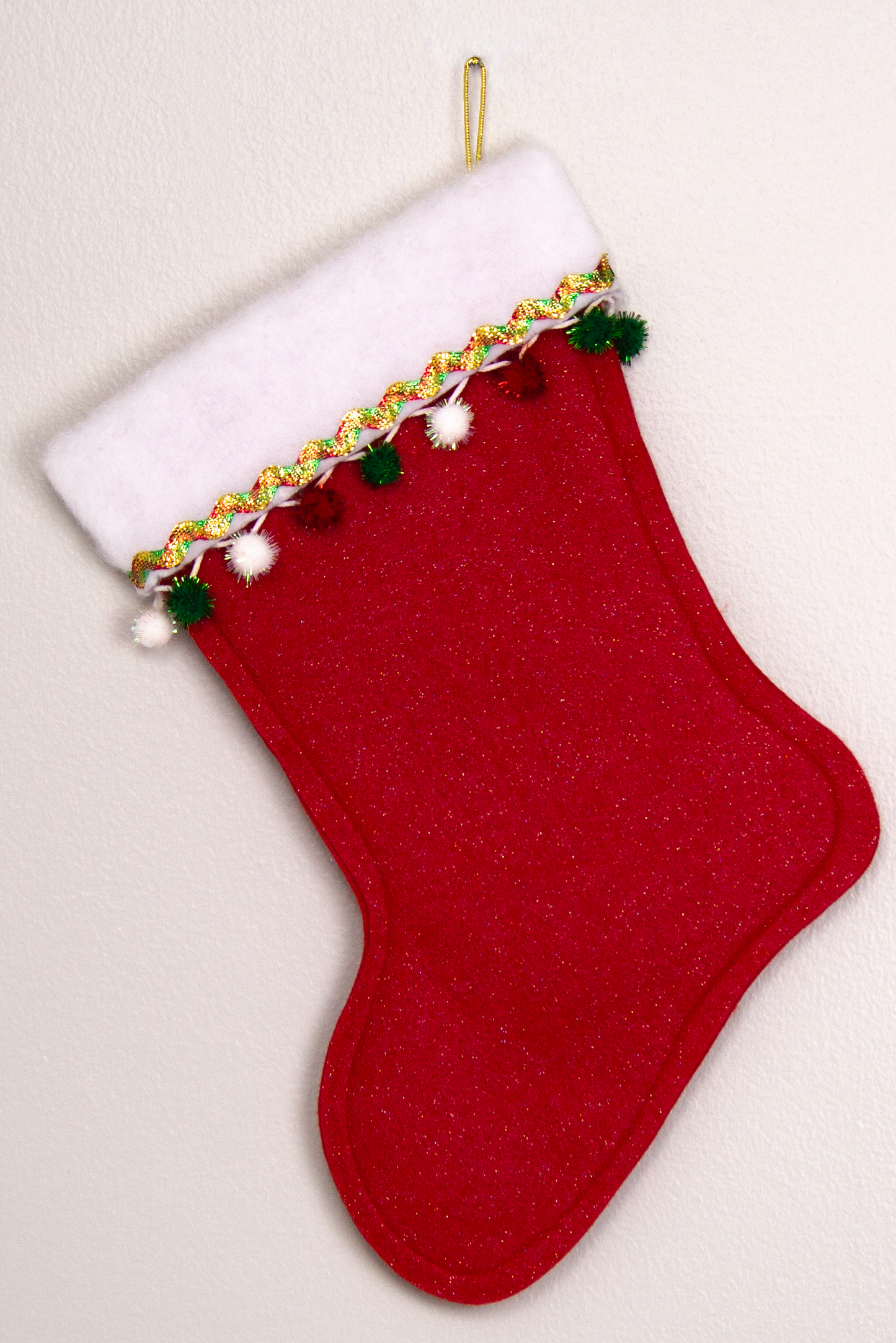 Red glitter felt handmade Christmas stocking with sparkly pom poms and decoration in red, green, white & gold. (back of triangle Santa stocking)